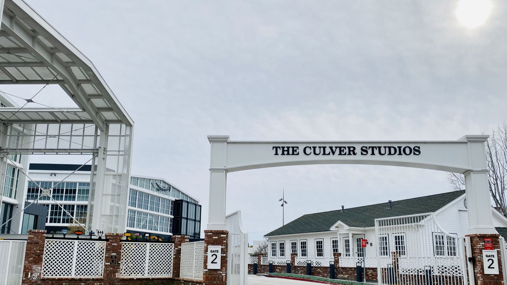 White arched entry gate reading “The Culver Studios” with modern buildings and Gate 2 signage.