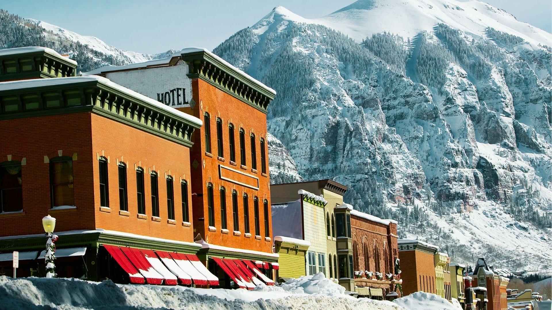 Historic red brick hotel and shops with snow covered awnings against towering snowy mountain backdrop