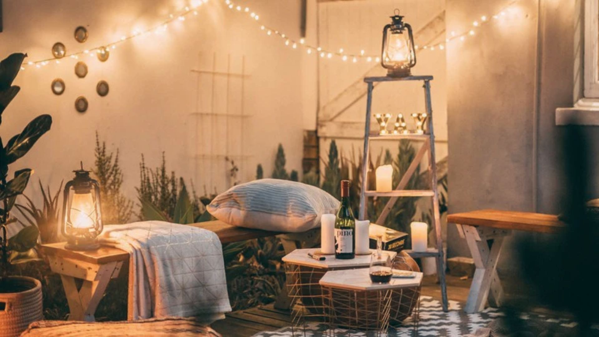 Magical outdoor movie setup with string lights, vintage lanterns, and candles on a patio.