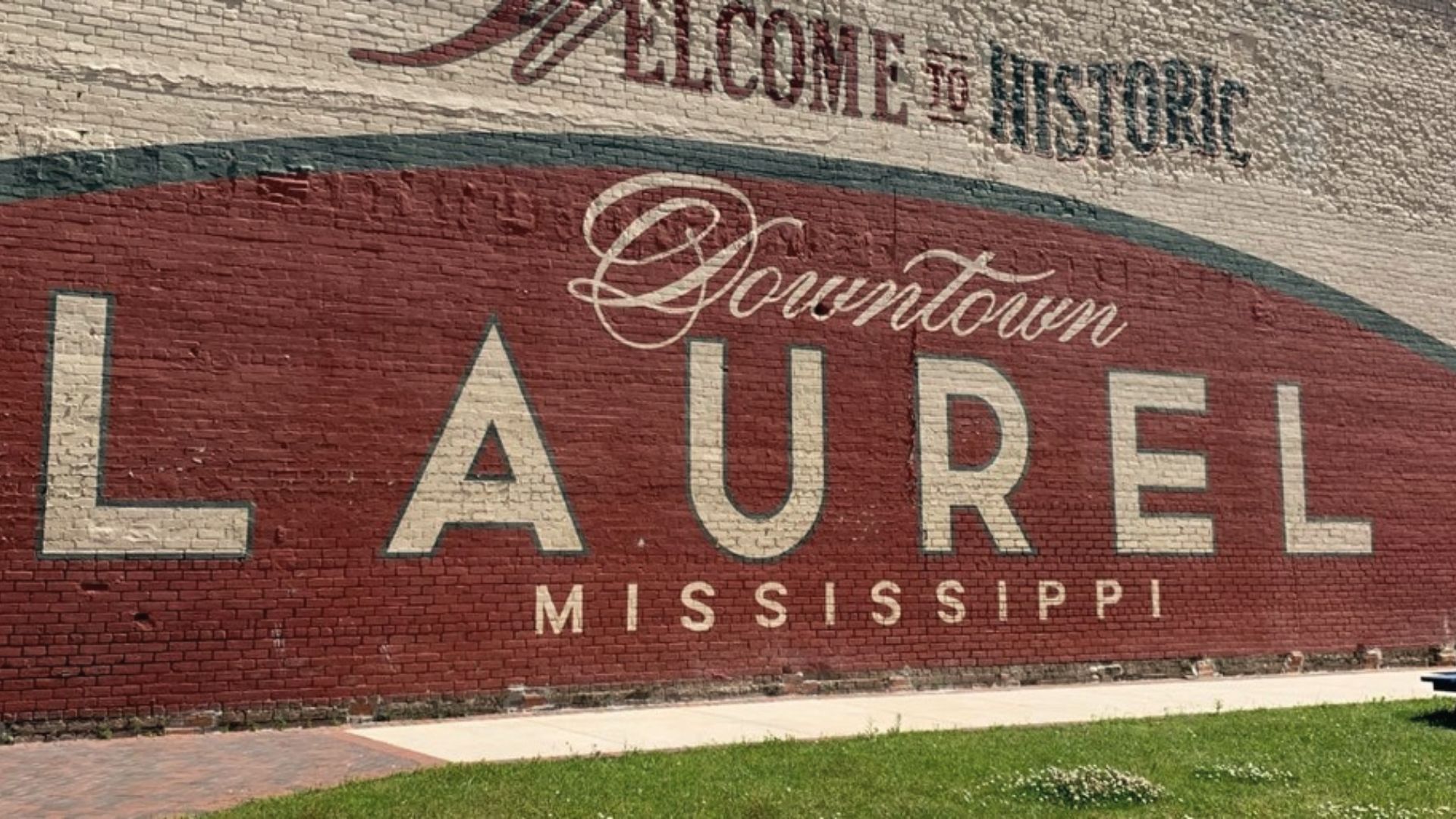 Close-up of the "Welcome to Historic Downtown LAUREL MISSISSIPPI" mural painted on red brick.