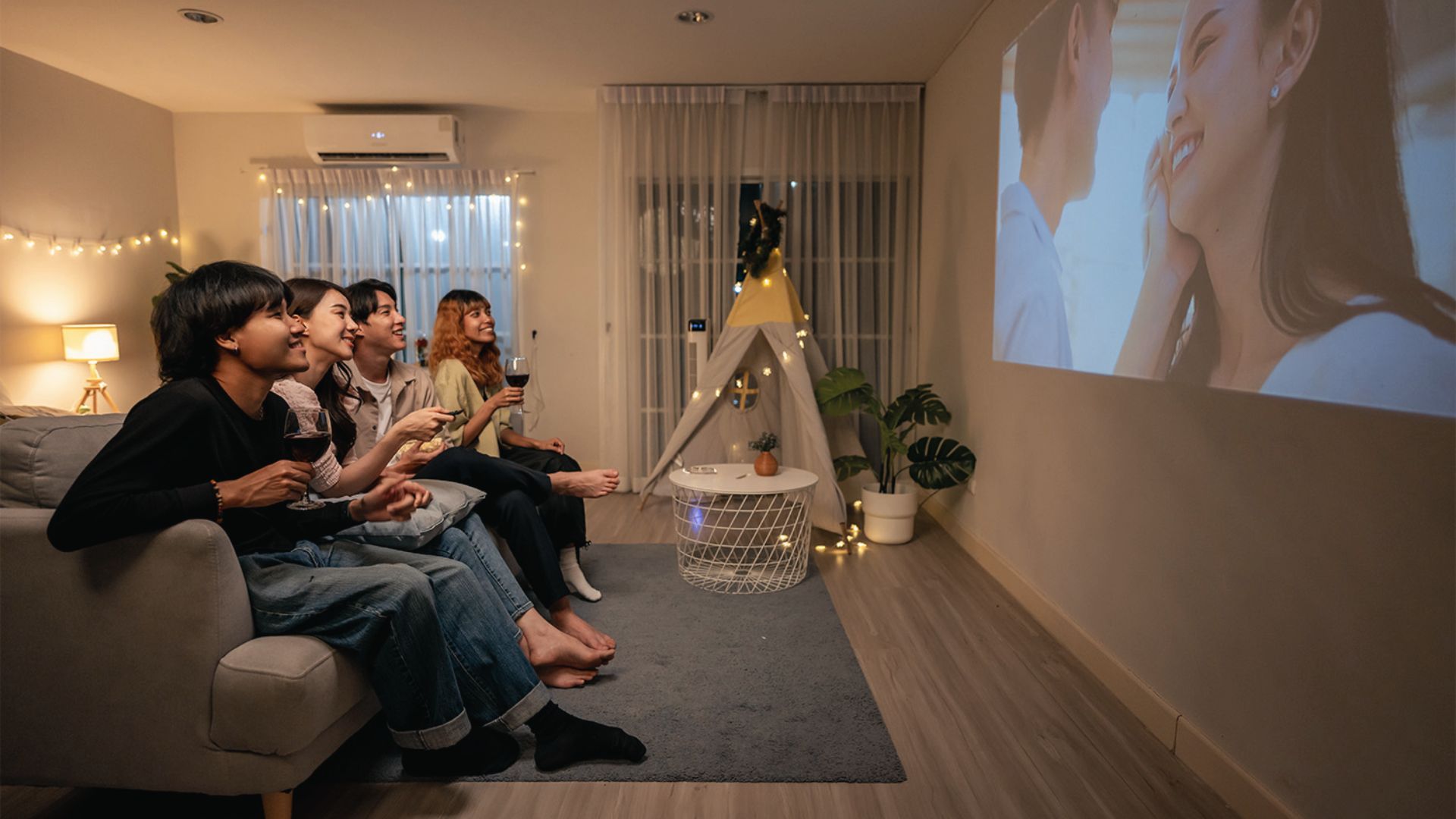 String lights, a cozy teepee tent, and indoor plants create a fun group movie night at home.