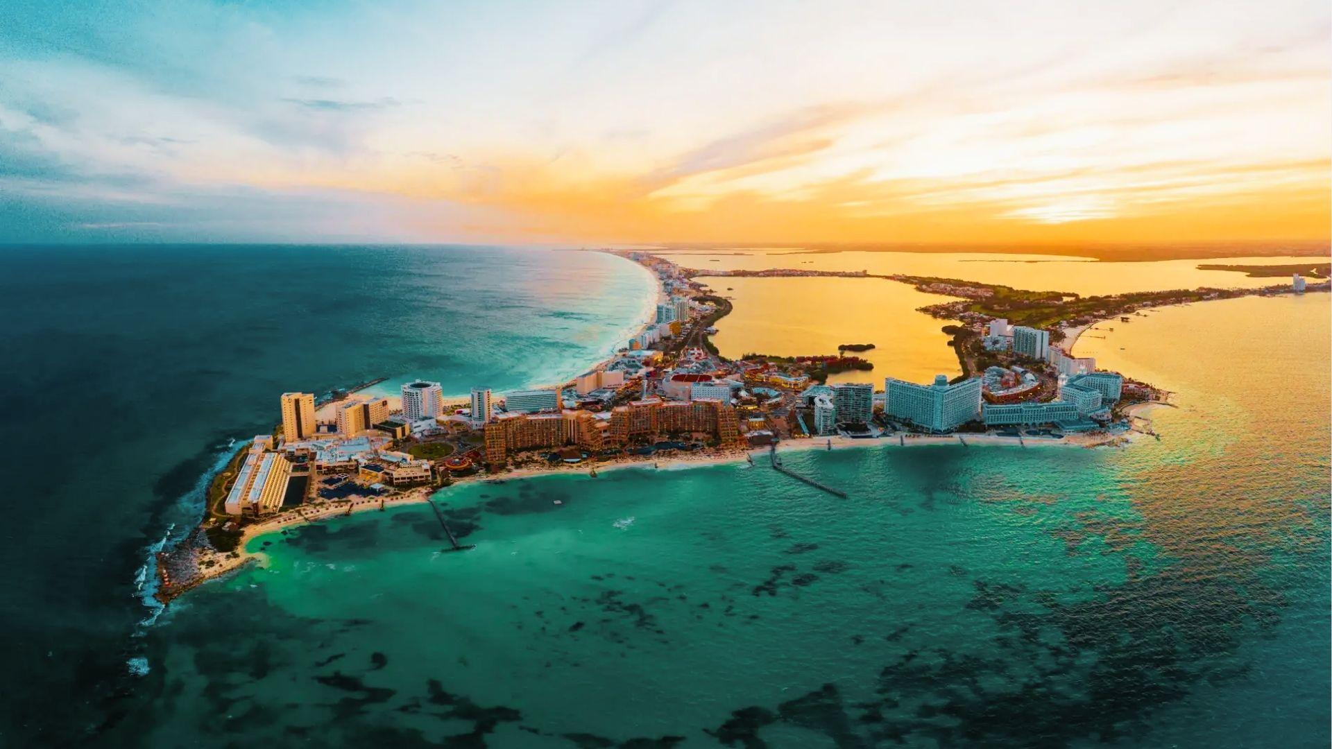 Aerial view of resort city on narrow peninsula between ocean and lagoon at golden sunset