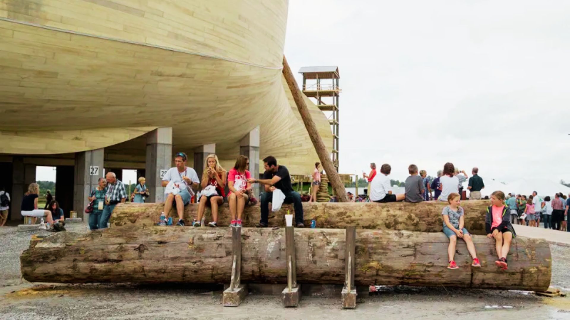 Visitors sit on massive logs for a break in front of the life-size Noah’s Ark structure in Kentucky.