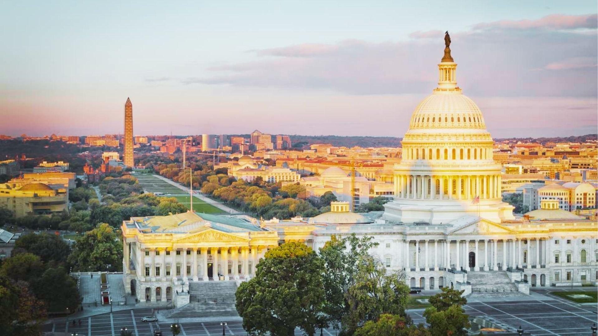 US Capitol building dome and Washington Monument glow at sunset with National Mall trees