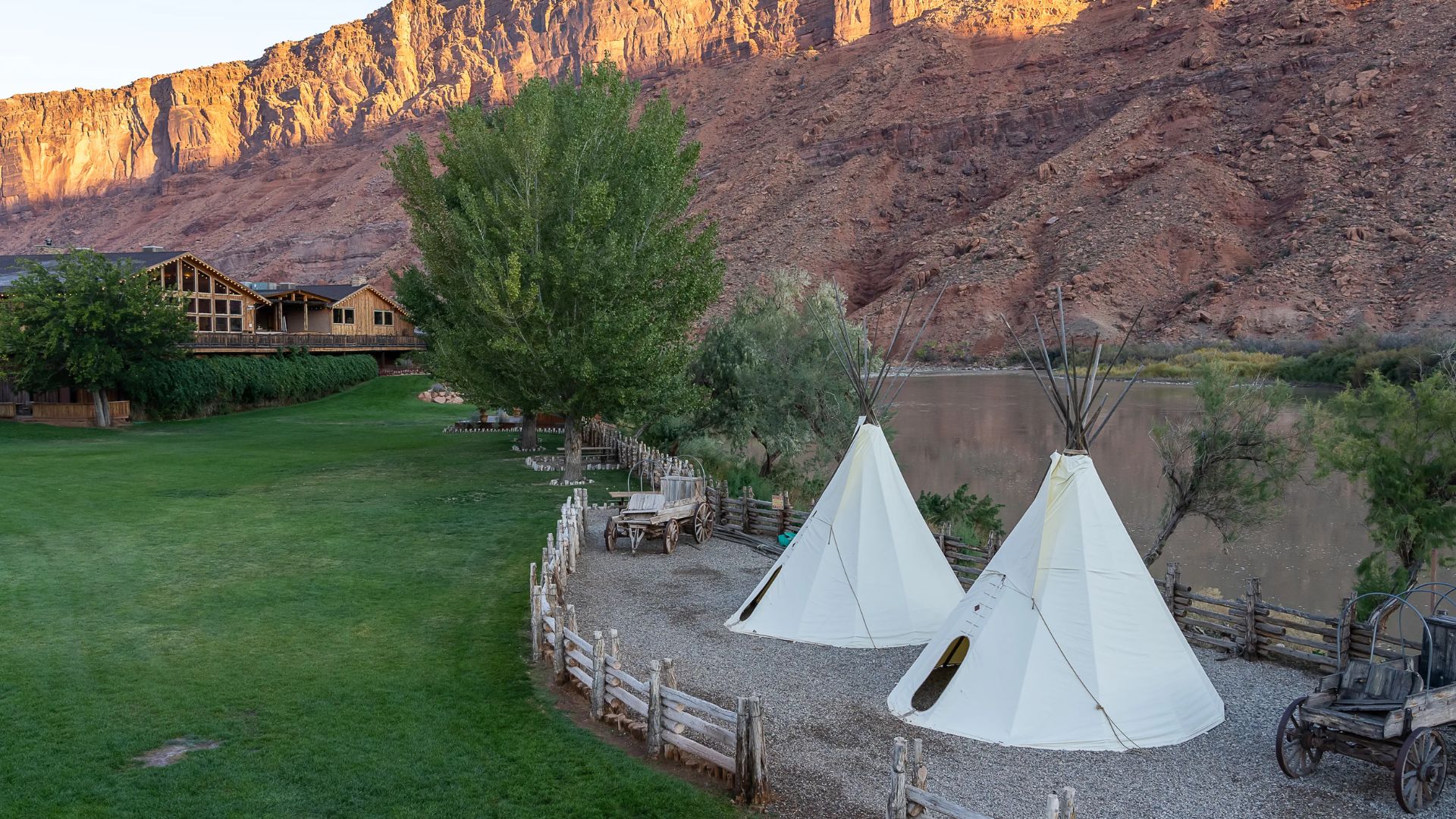 White canvas tipis and wagons along a river beneath red rock mesas in Moab, Utah, seen in The Rifleman.