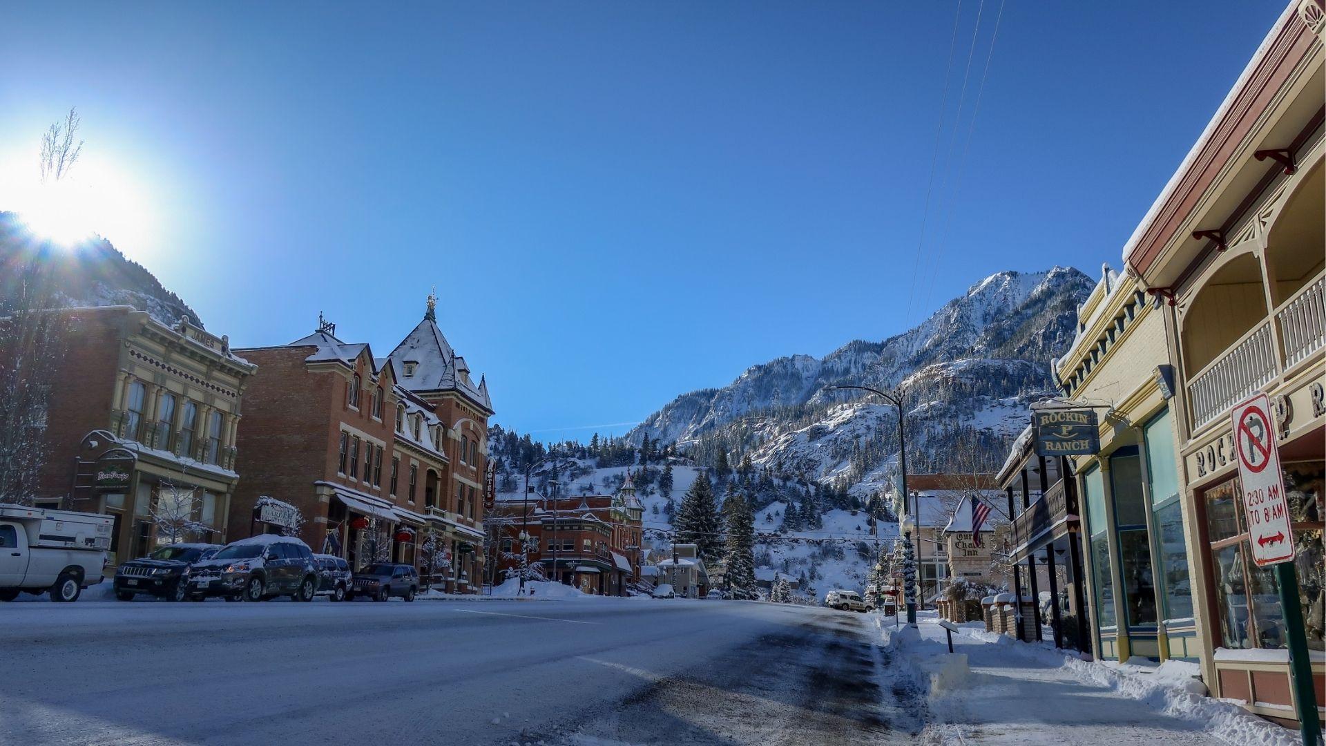 Historic brick buildings and hotel line sunny street with snowcapped mountains and green hills