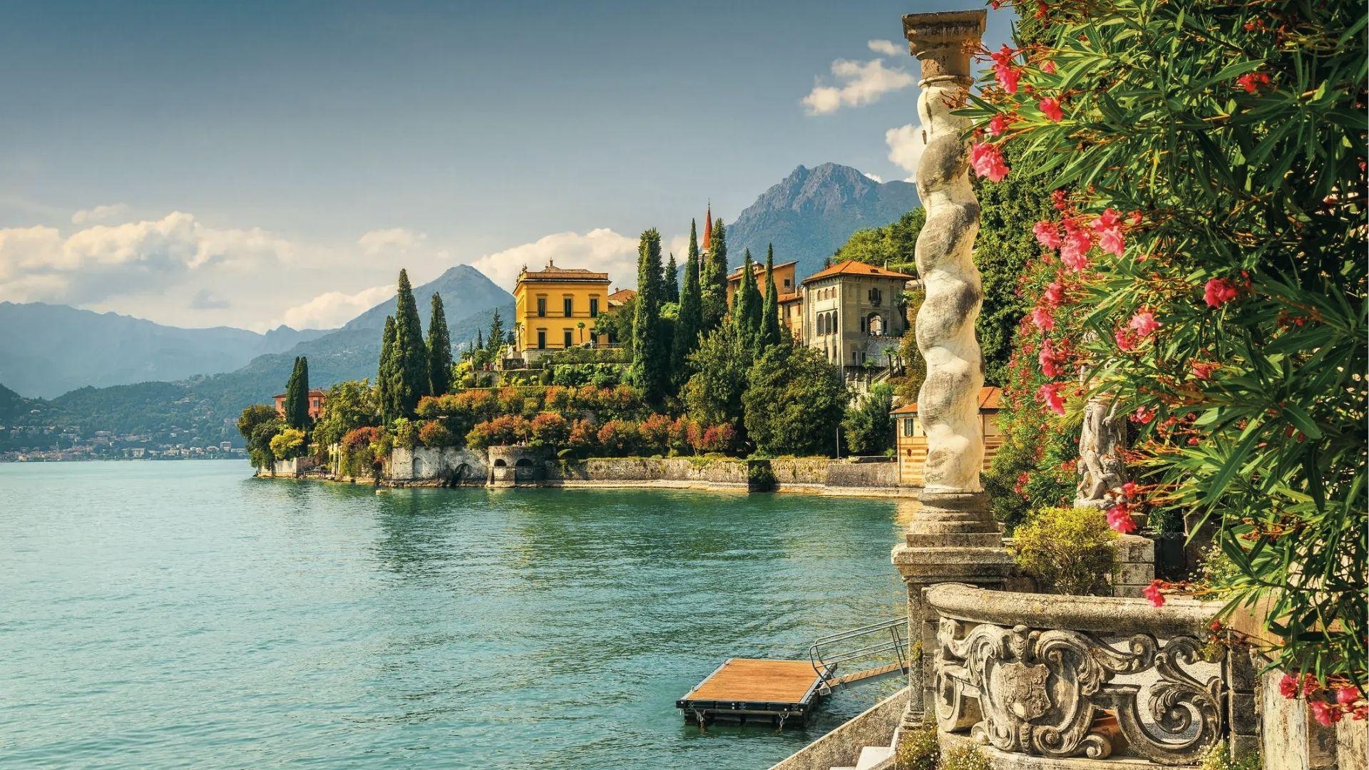 Ornate stone balustrades and pink oleander frame a view of Villa Monastero on Lake Como.