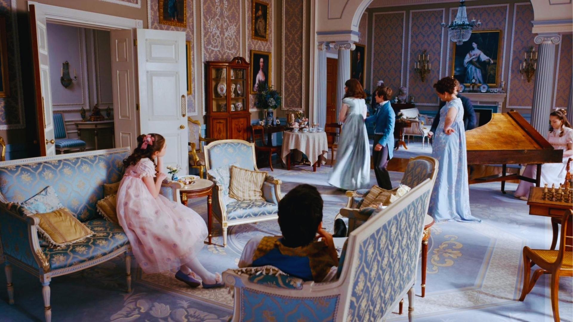 Bridgerton drawing room with pale blue walls, blue-gold settees, and Regency family dancing near grand piano.