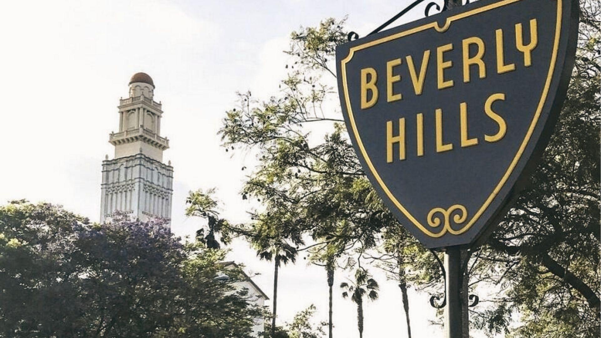 The Beverly Hills shield sign appears in the foreground with the Beverly Hills City Hall tower visible behind it.