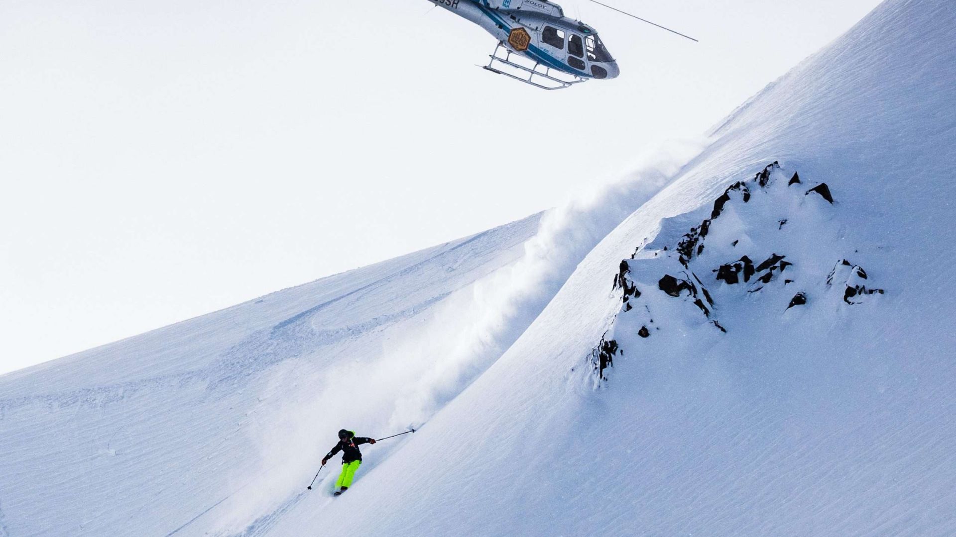 A PHOTO OF A MAN DROPPING FROM HELISKIING
