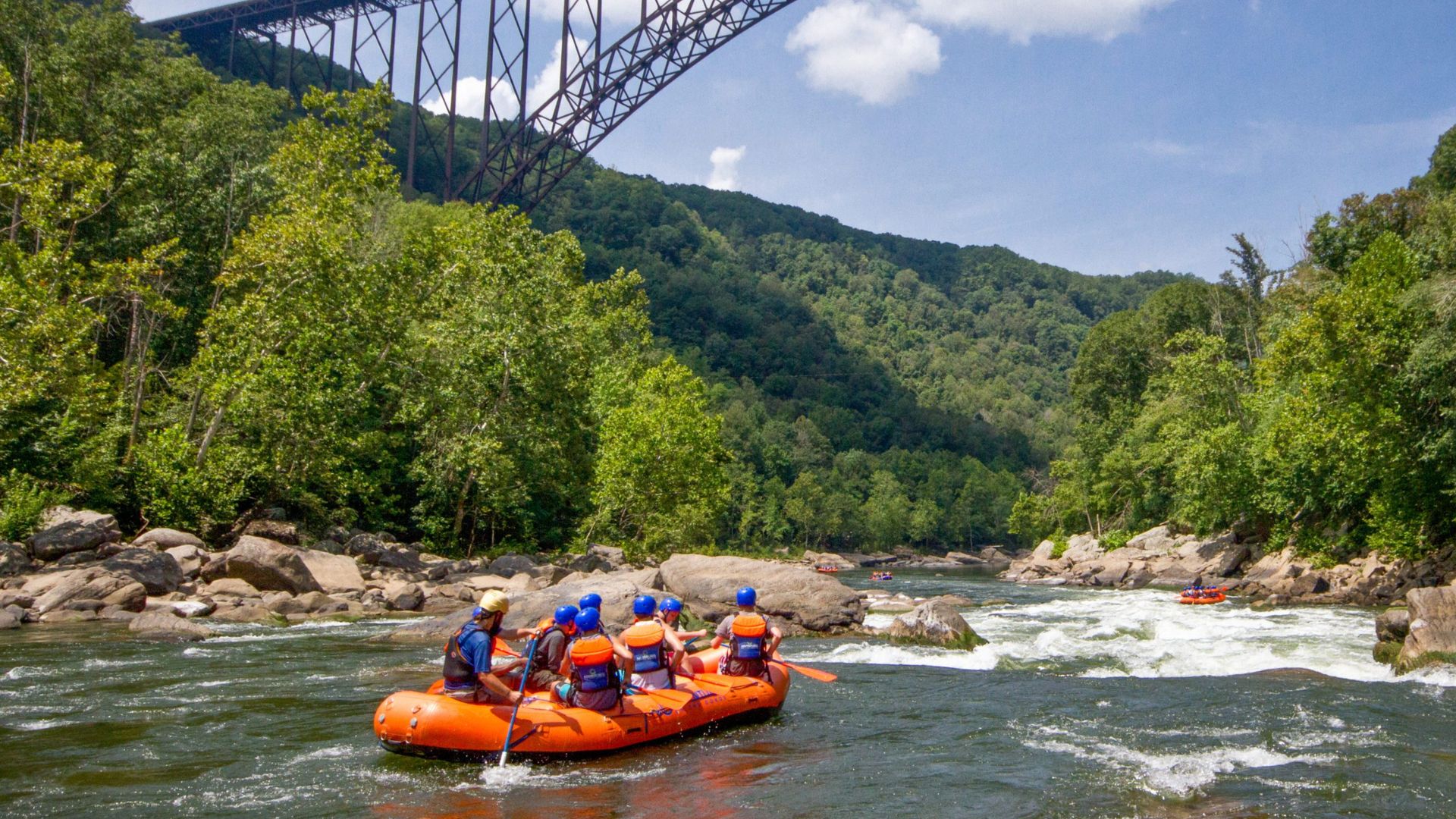A GROUP OF PEOPLE RAFTING IN WHITEWATERS
