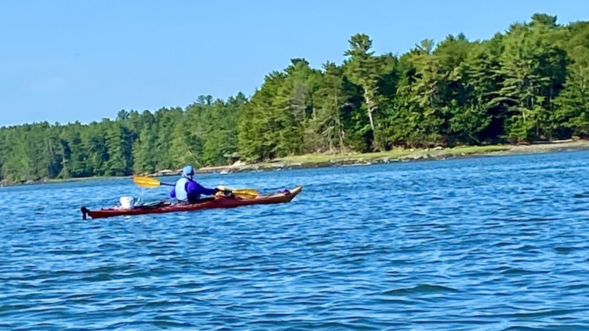 A MAN KAYAKING FOLLOWING THE MAINE ISLAND TRAIL
