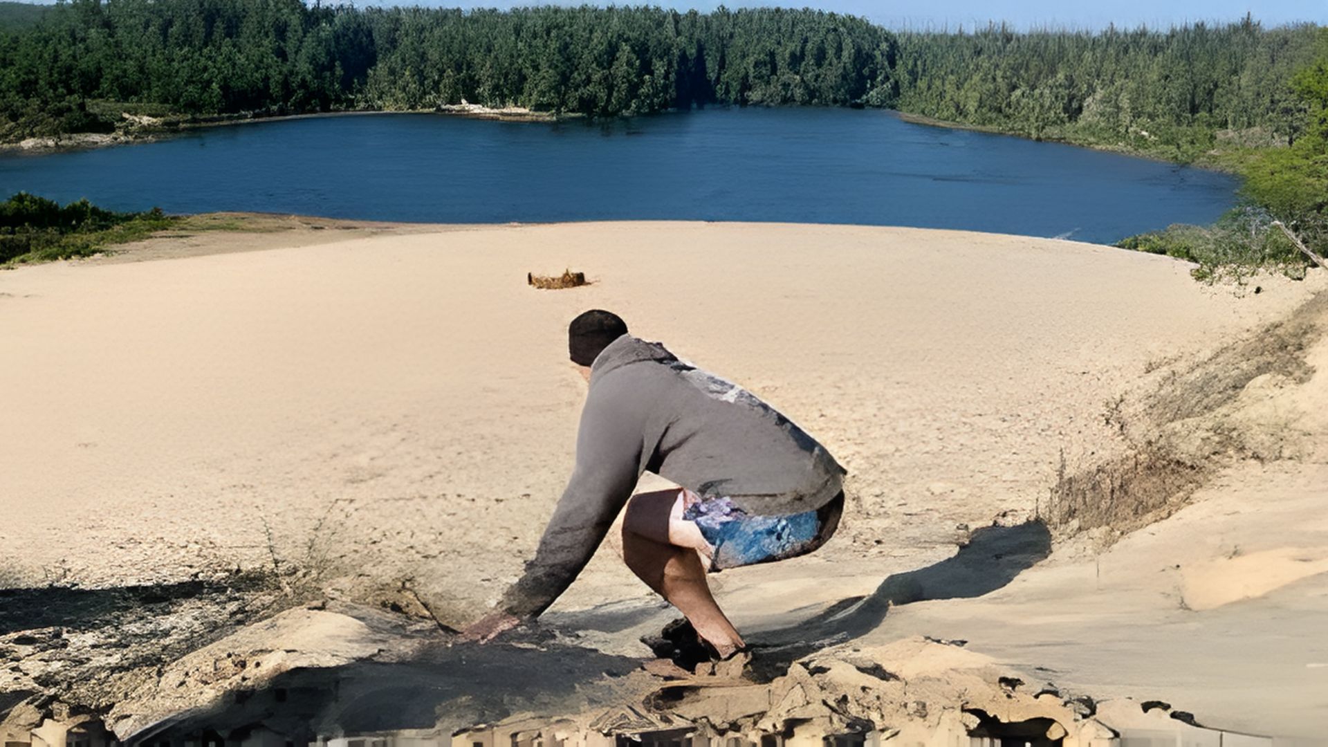 A MAN PREPARING TO SANDBOARD ON COASTAL DUNES
