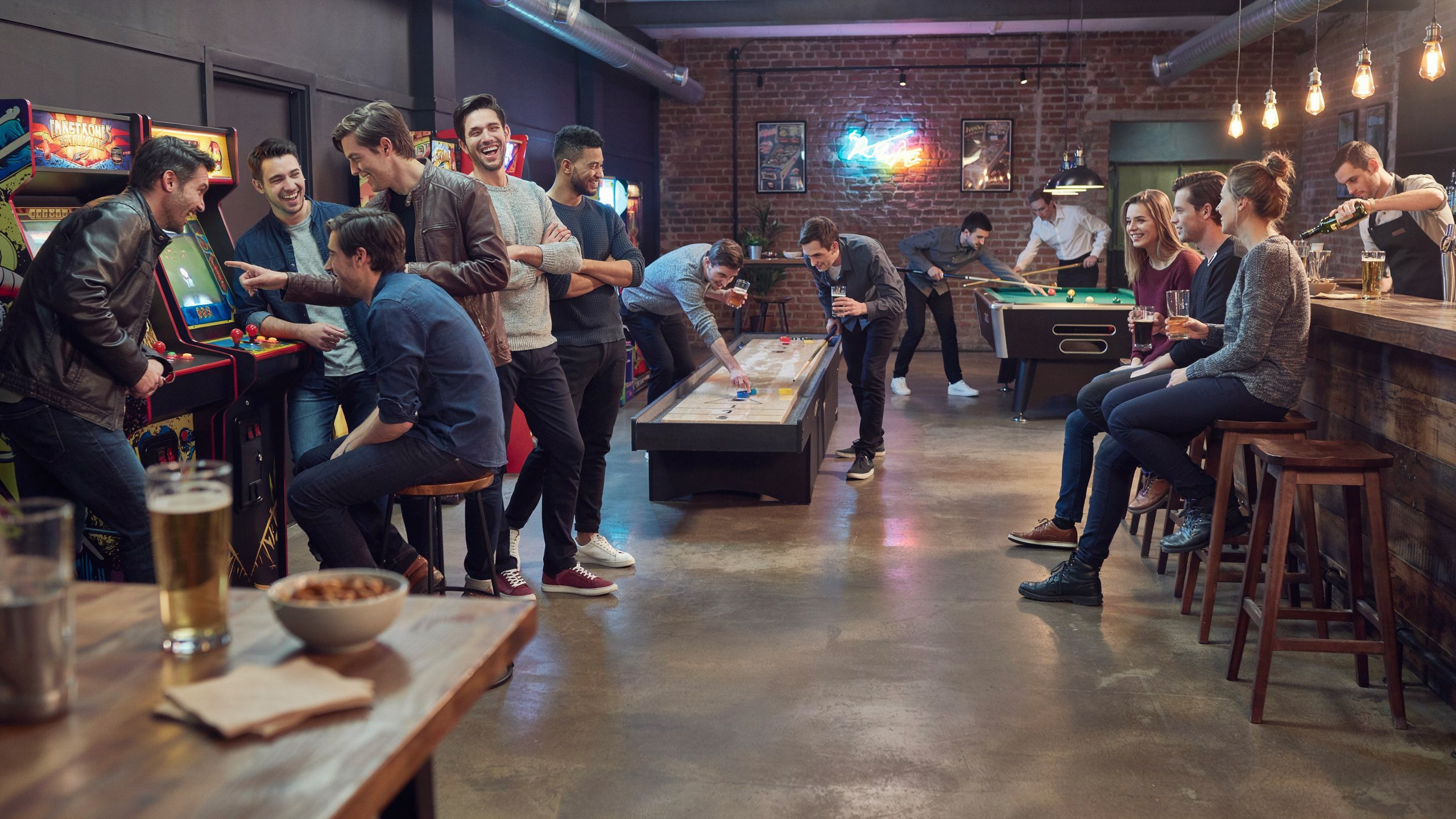 A group of friends enjoying games together in a lively bar setting, with drinks and laughter surrounding them.