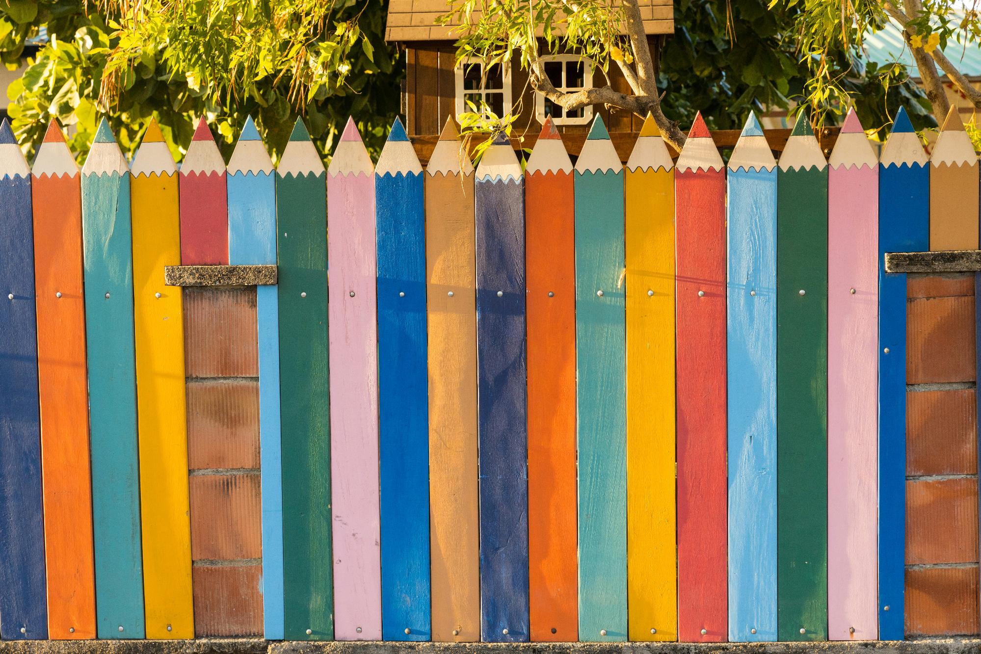 A vibrant fence adorned with colorful pencil designs, showcasing a playful and artistic theme.