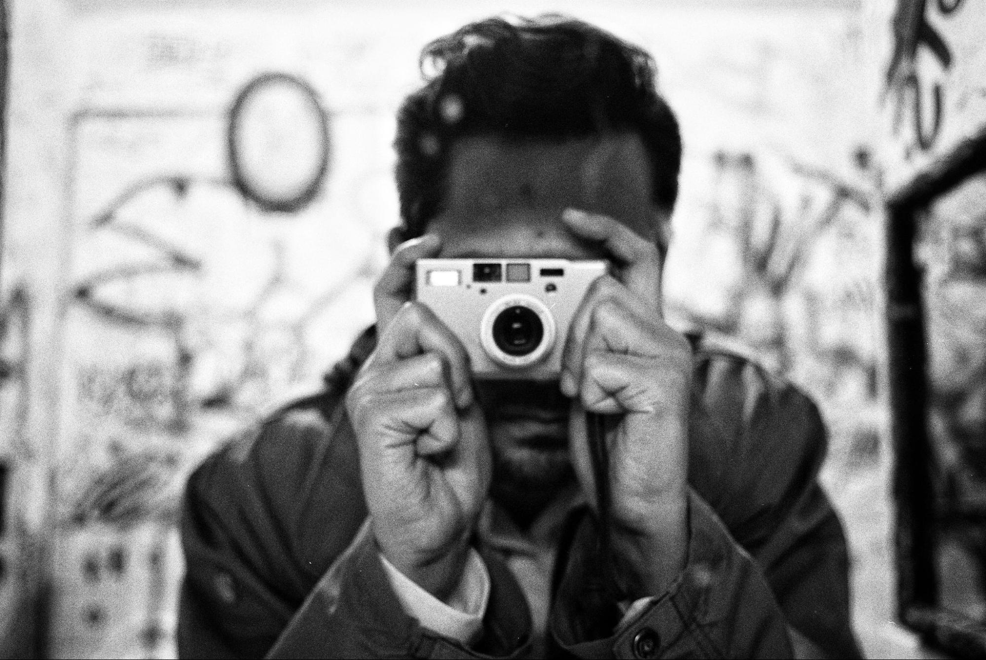 A man photographs a vibrant graffiti wall, capturing the colorful street art with his camera.