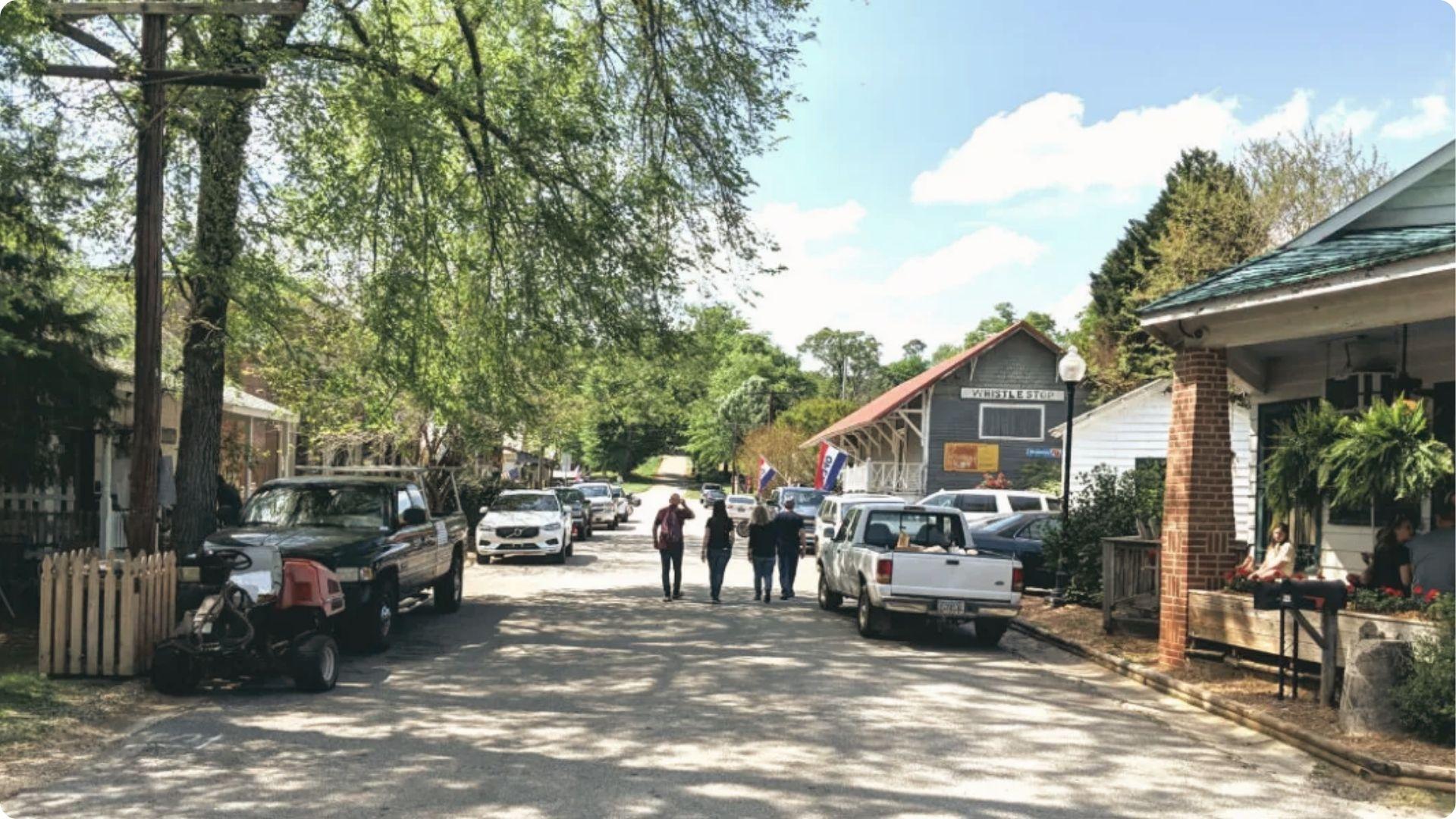 Street view of Juliette with parked cars, Whistle Stop depot building, visitors walking.