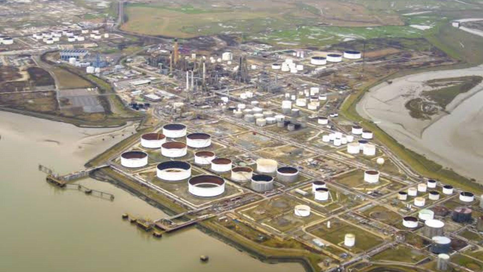 Aerial view of Coryton Oil Refinery with large cylindrical storage tanks along the waterfront.