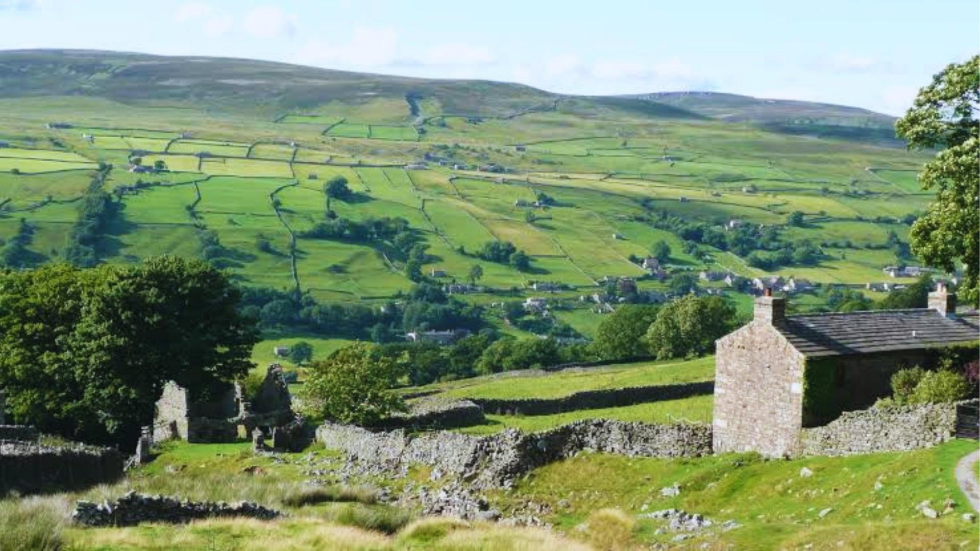 Stone cottage ruins overlooking lush green dales in Yorkshire, landscape featured in Wuthering Heights adaptations.