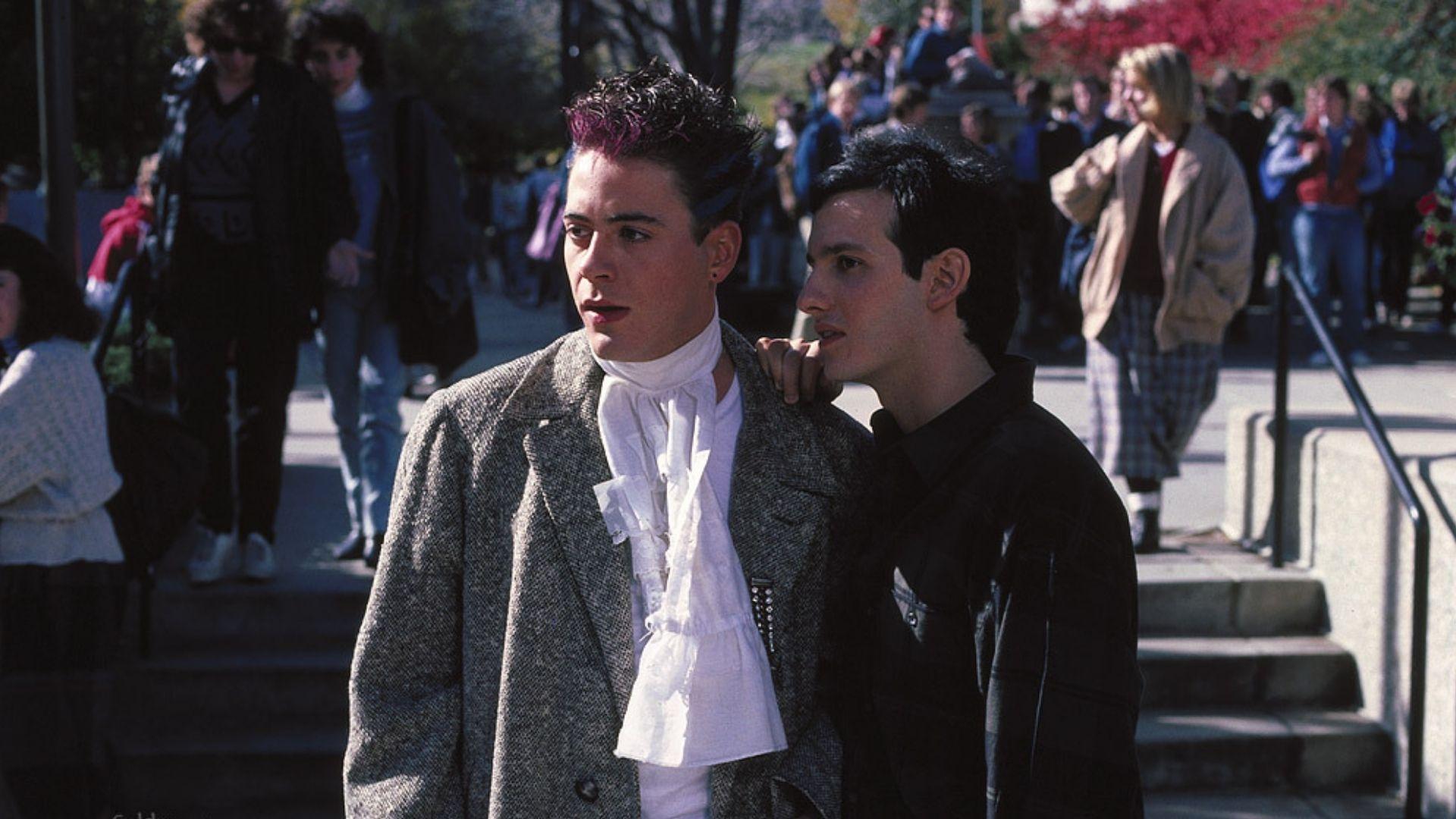 Two young men talk on a busy college campus in autumn in Back to school.