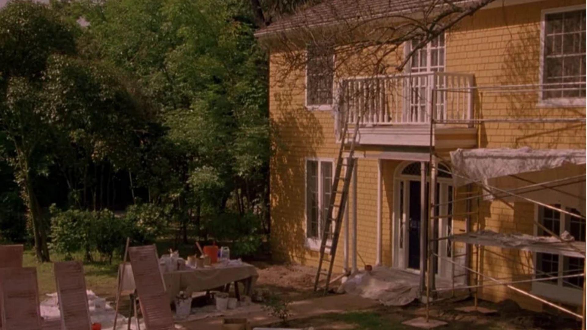 A yellow clapboard house from American Pie 2 under renovation with equipment in the backyard.