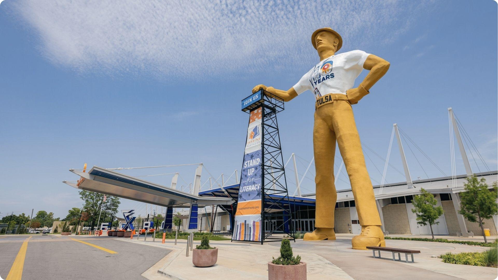 Golden Driller statue with Tulsa belt and oil derrick stands outside the Expo Square in Tulsa, a landmark featured in Tulsa King filming.