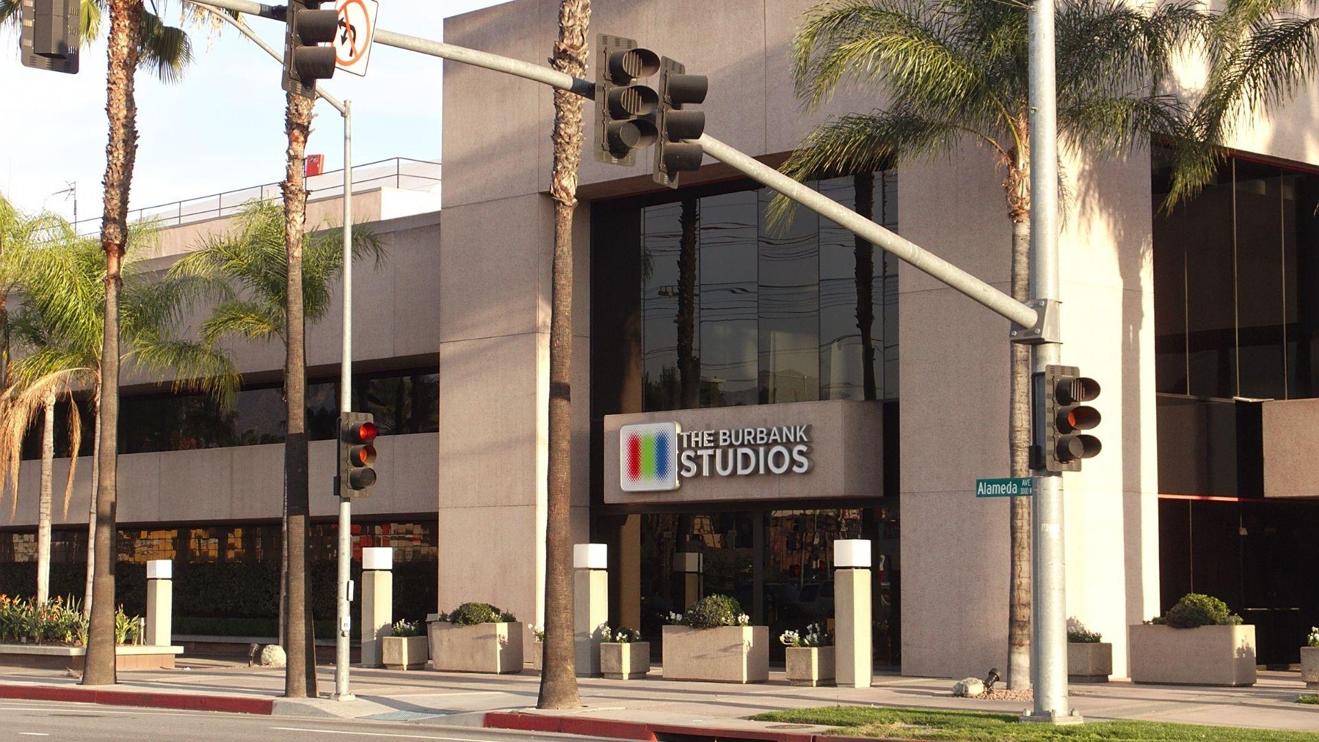 Still from NOPE. Exterior of The Burbank Studios on Alameda Ave, Burbank, flanked by palm trees.
