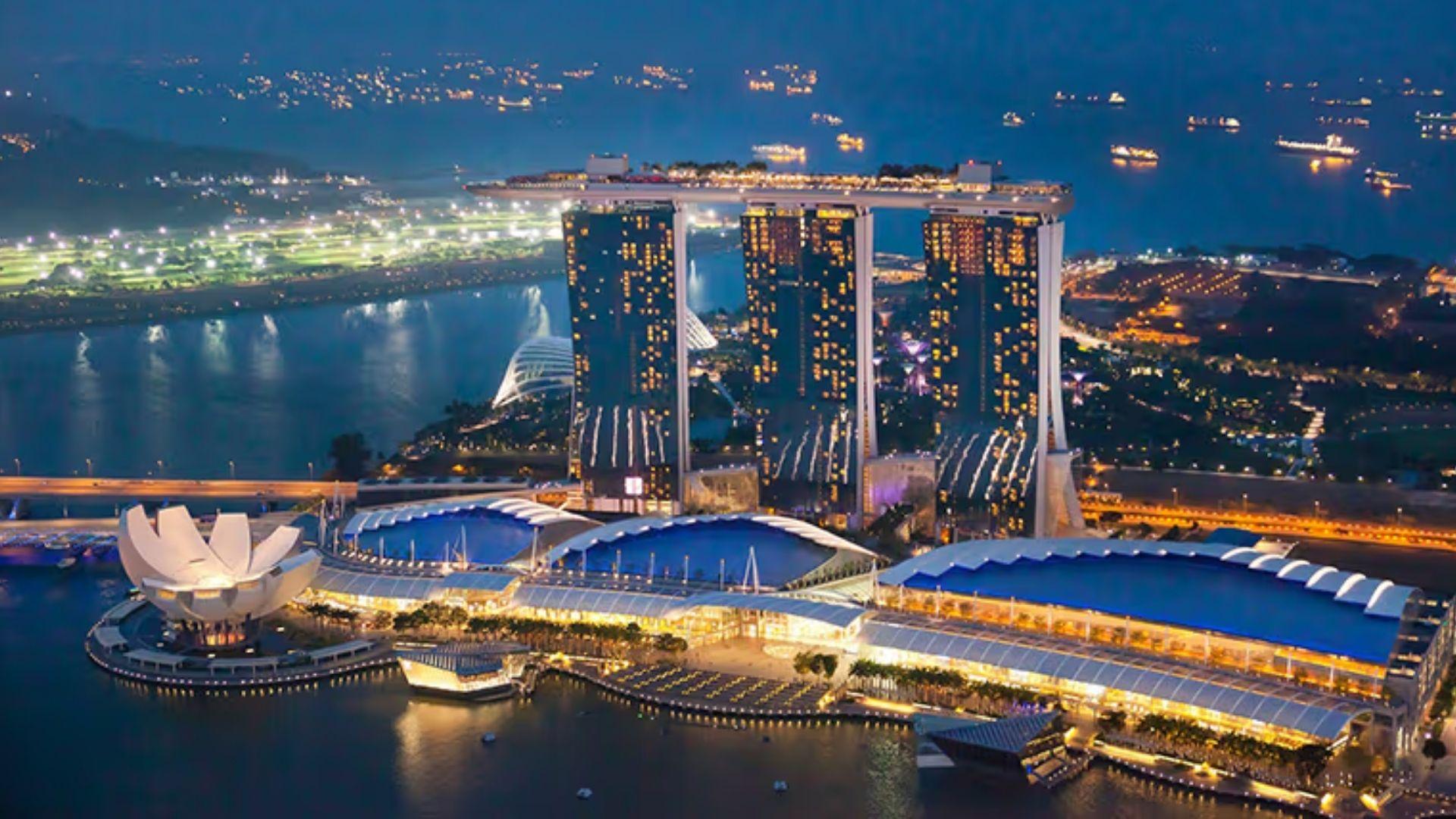 Aerial night view of Marina Bay Sands and the ArtScience Museum amid Singapore's glittering waterfront.