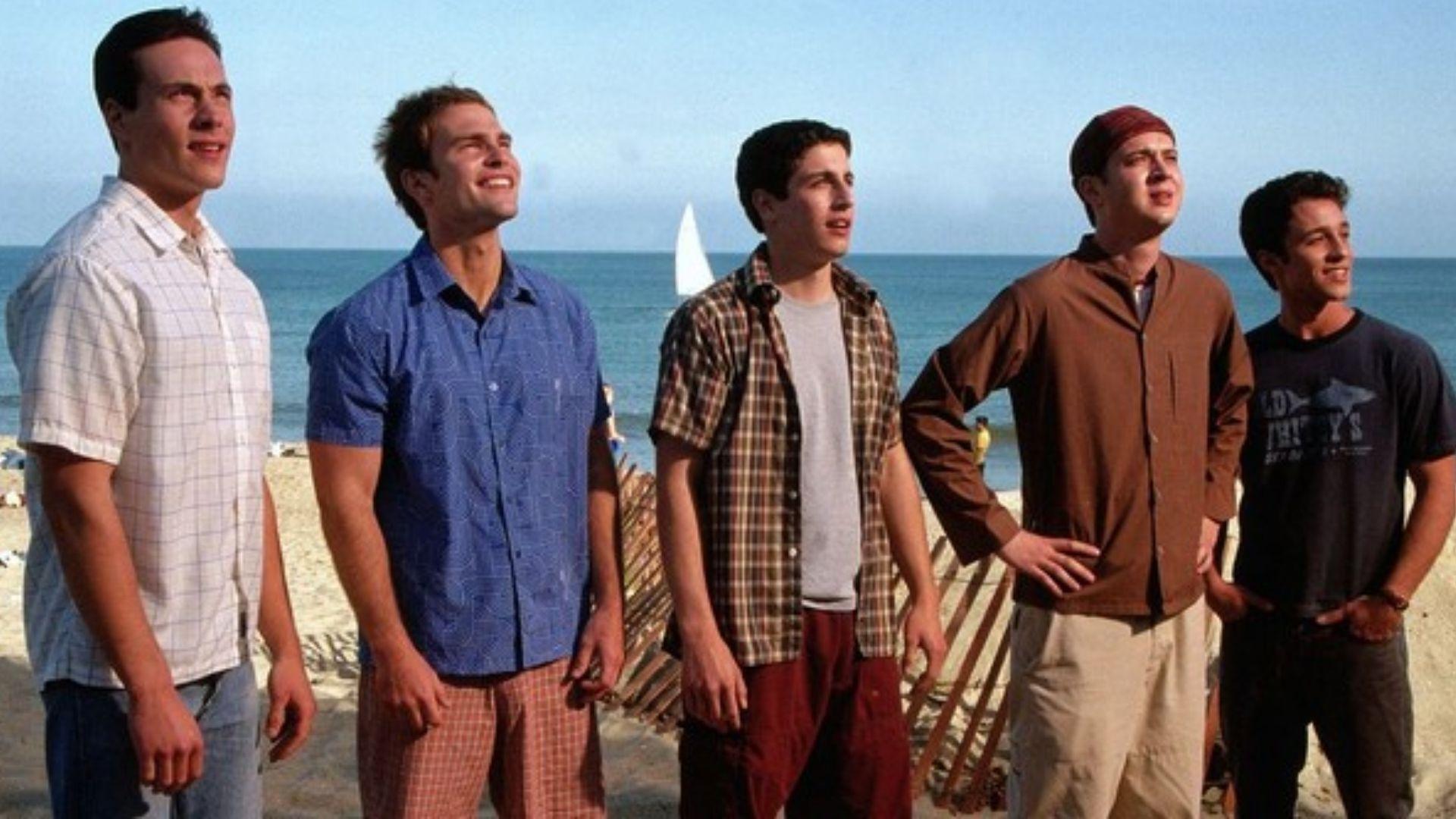 The main cast of American Pie 2 stand side by side on a sunny beach, smiling and looking into the distance.