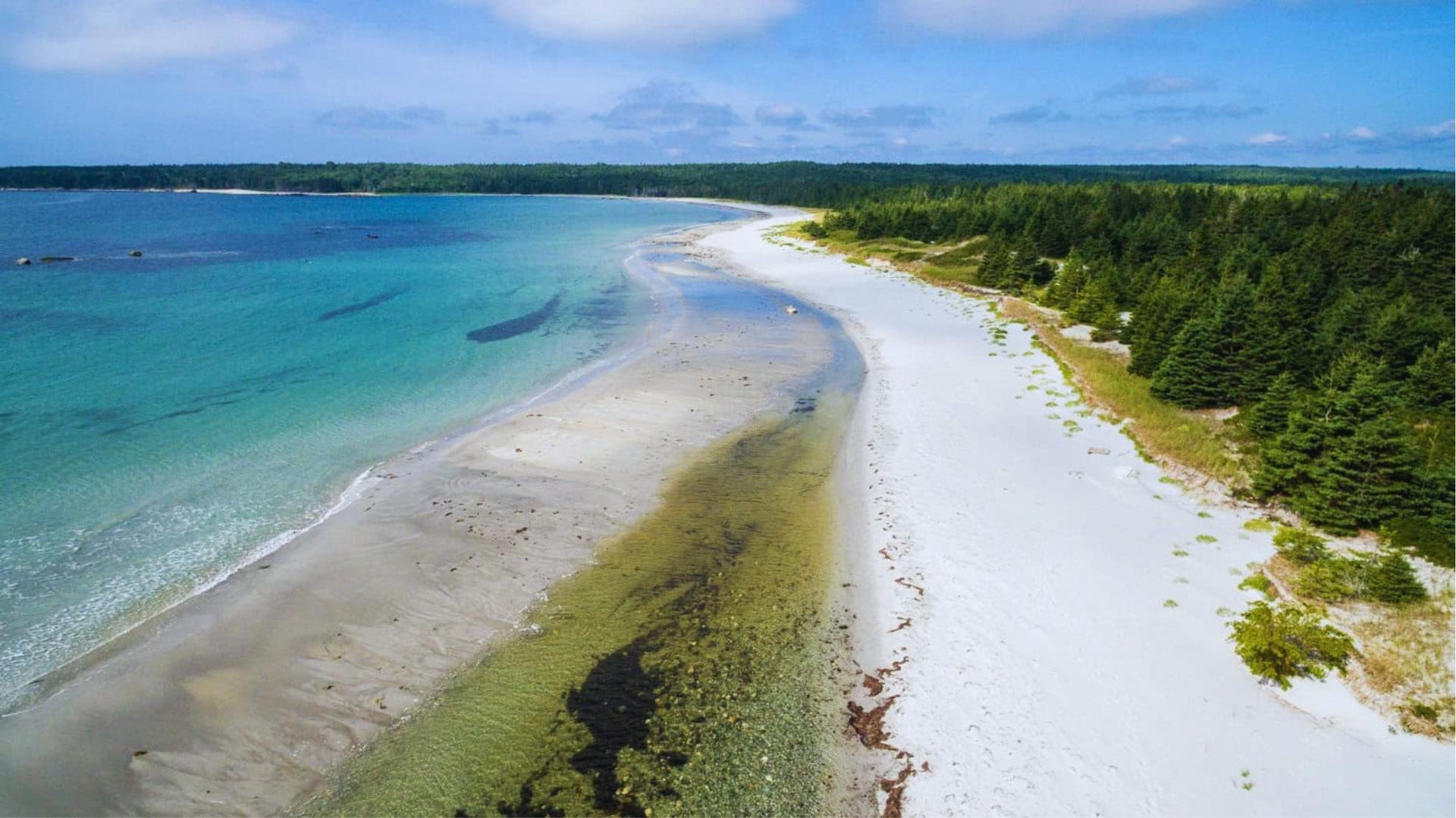 Aerial of white sand beach and turquoise water at Crescent Beach, Nova Scotia, filming location for We Were Liars.