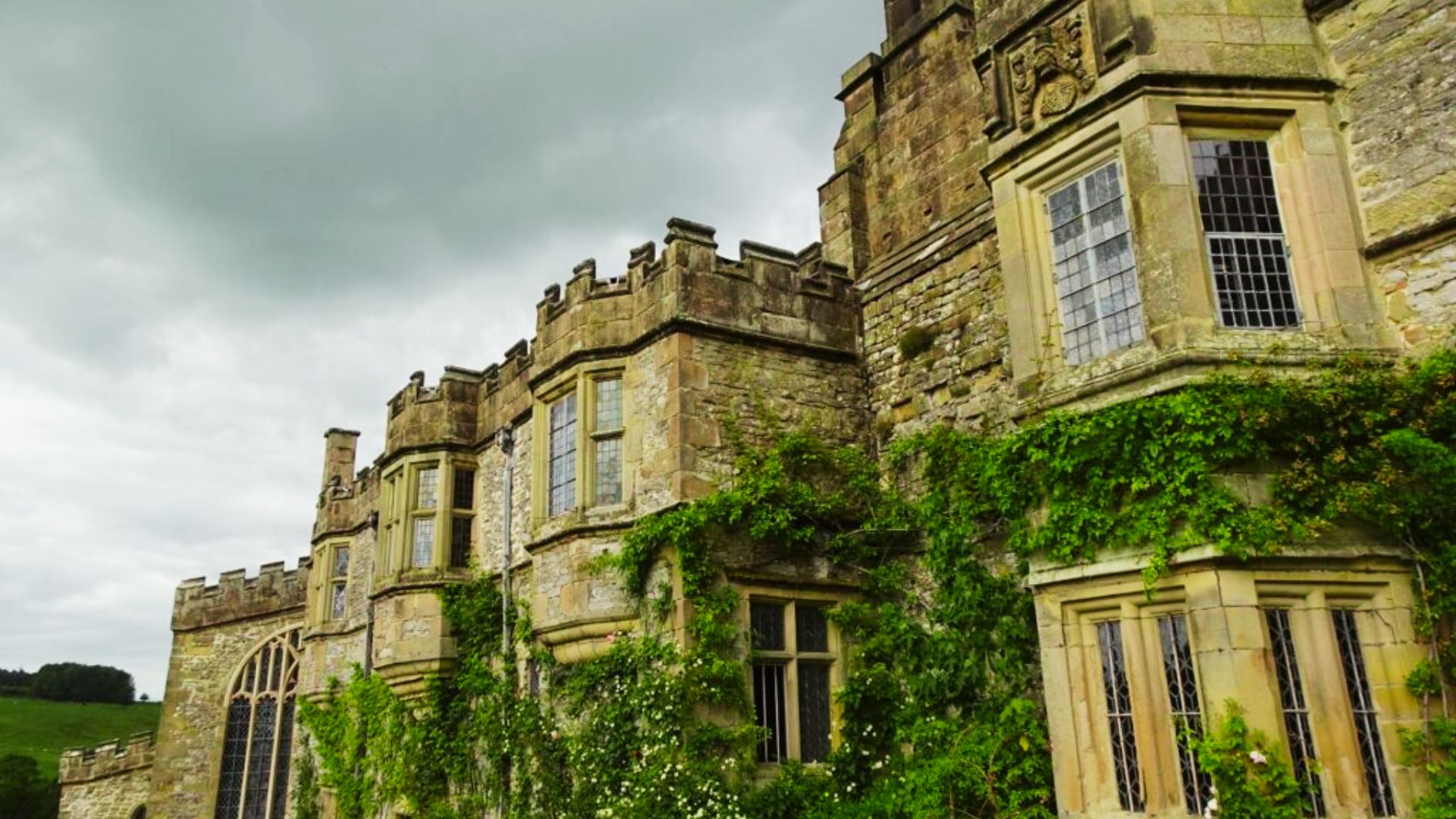Weathered stone stairs lead to an arched doorway in Haddon Hall's historic courtyard.