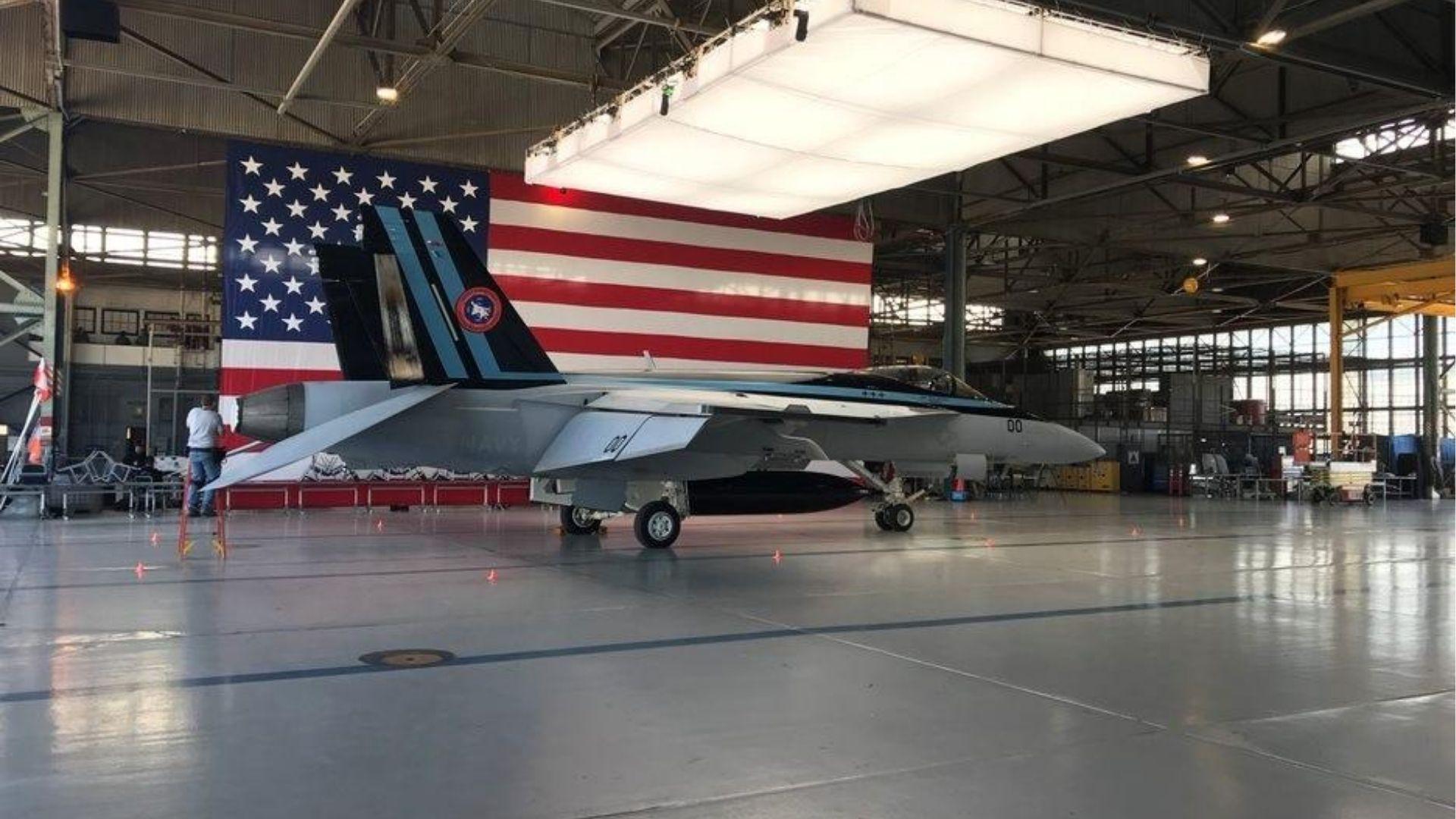 F/A-18 Super Hornet displayed inside a naval aviation hangar in a behind-the-scenes Top Gun: Maverick setting.