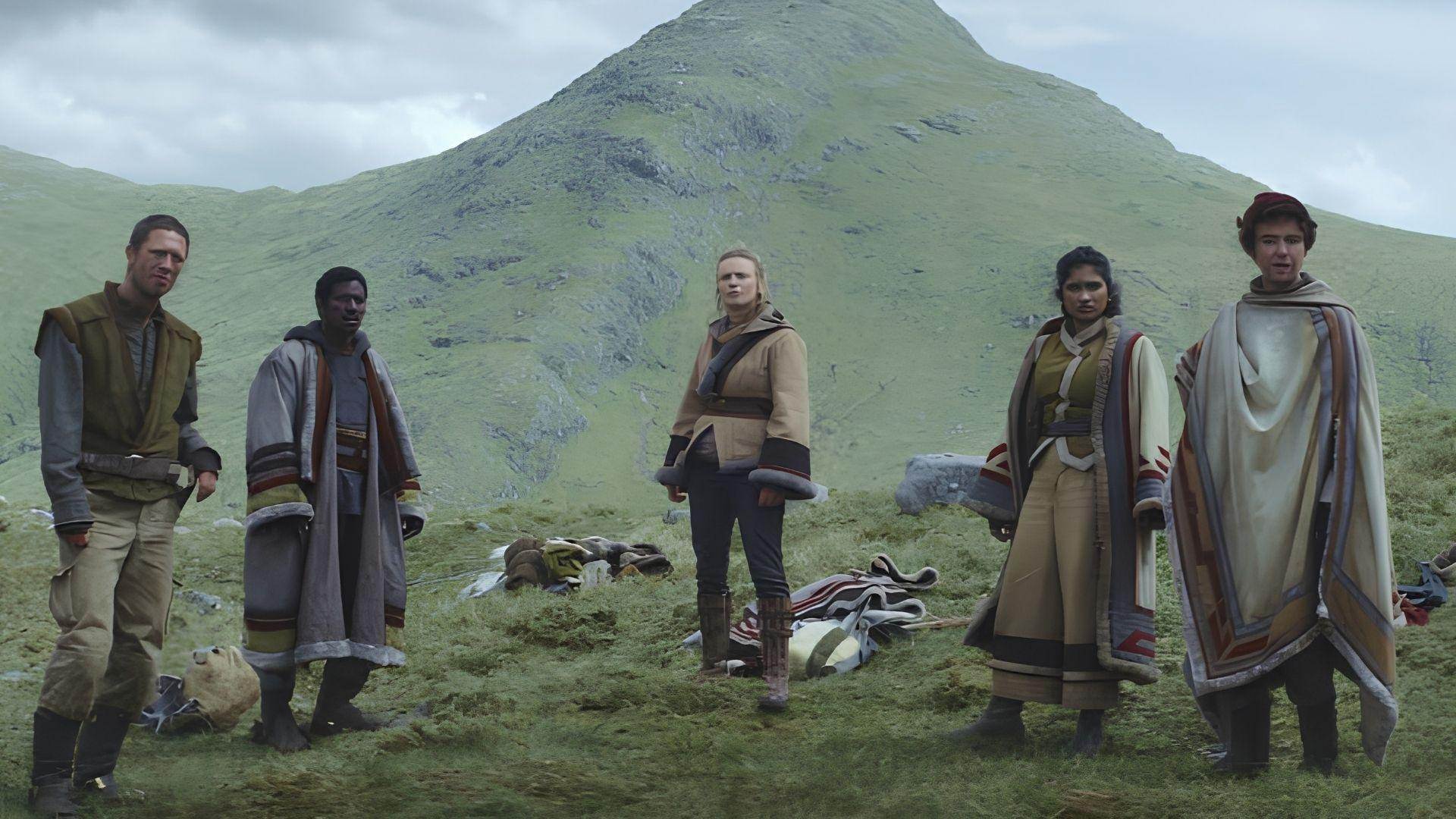 Five characters in sci-fi costumes on Highland moorland with a dramatic mountain behind them.