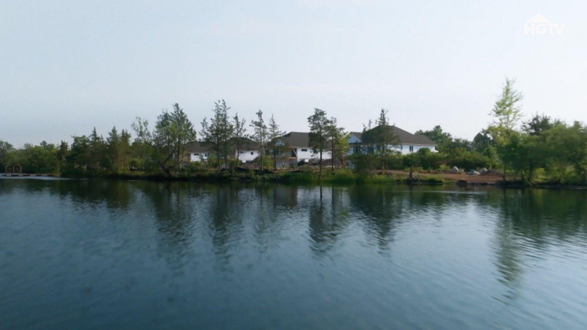 Renovation Resort Showdown. HGTV aerial shot of white lakeside homes hidden behind tall trees.