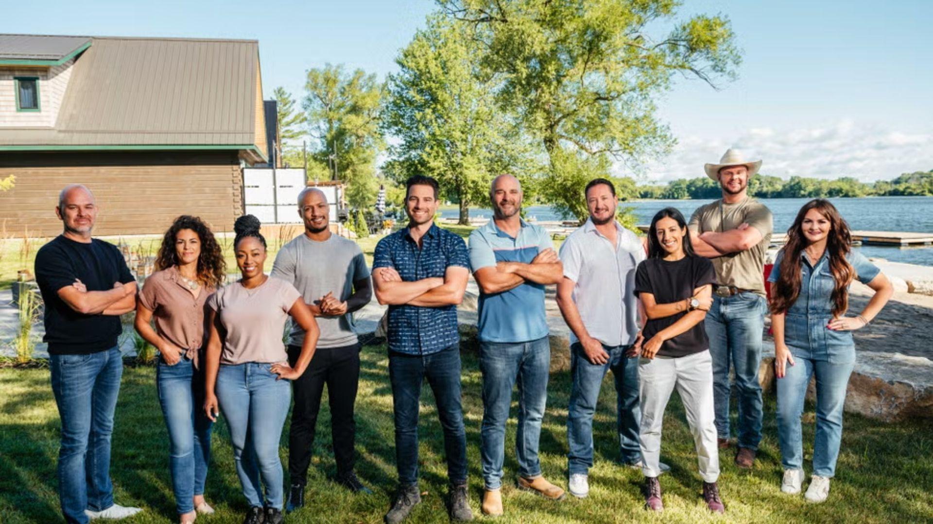 Renovation Resort Showdown. Full cast of contestants and hosts pose in a line on a green lakeside lawn.