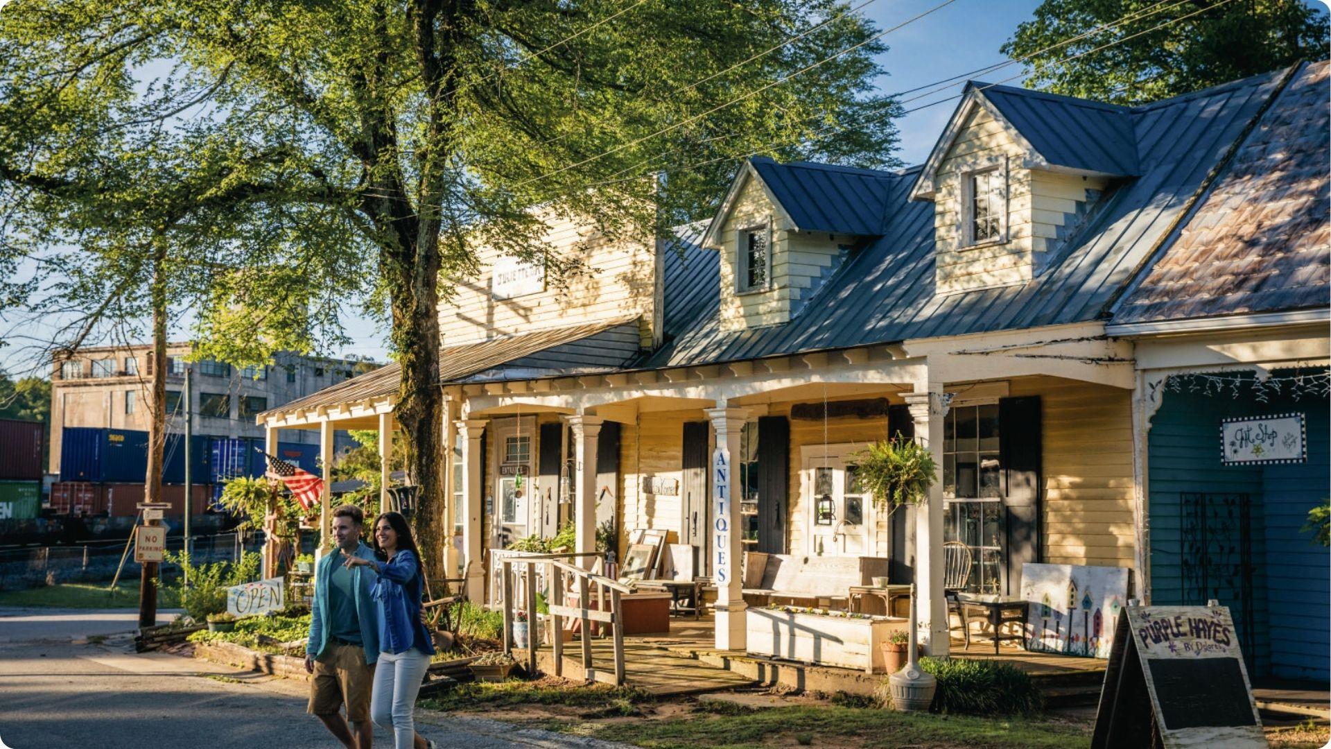 A couple walking past antique shops and gift stores on sunny main street in Juliette, Georgia.