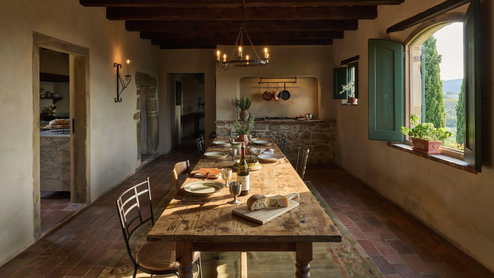 Tuscan Mediterranean interior with stone walls, wood beams, and warm golden earthy tones in a rustic space.