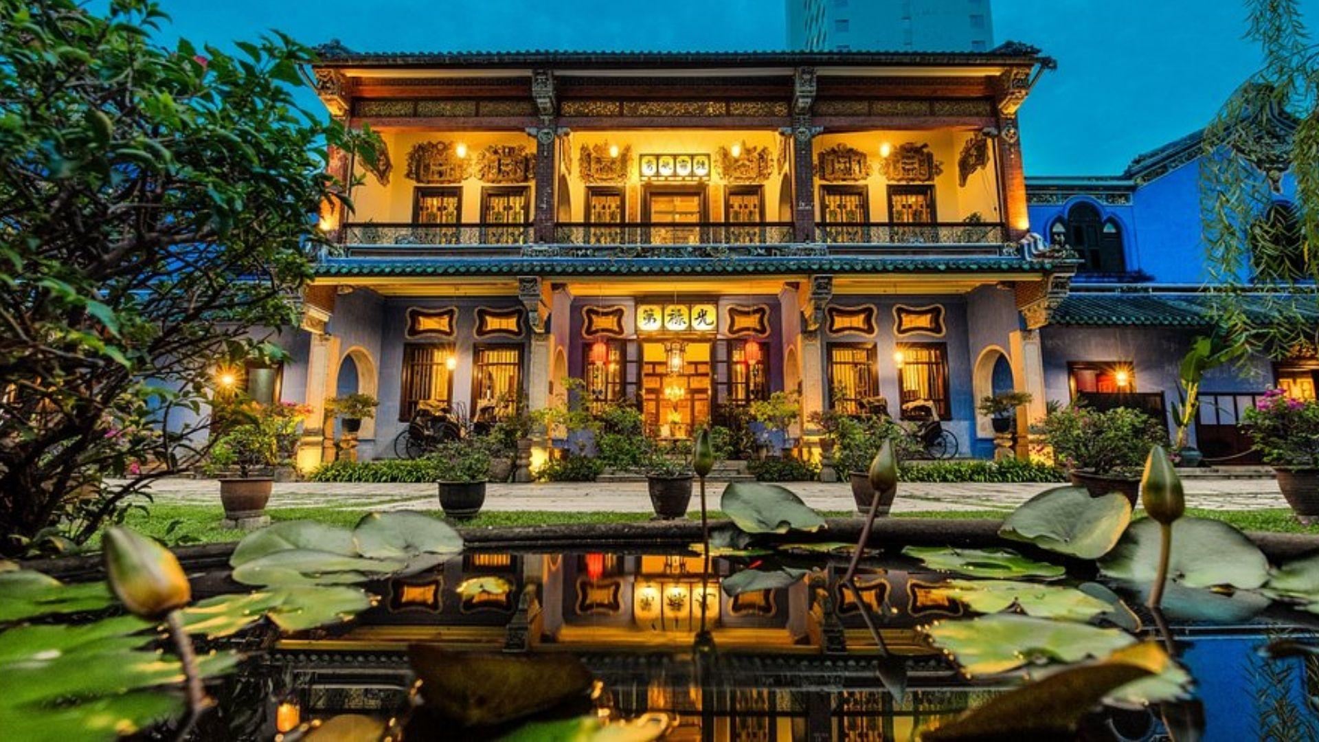 The Cheong Fatt Tze Mansion in Penang lit up at night, reflected in a lotus pond.