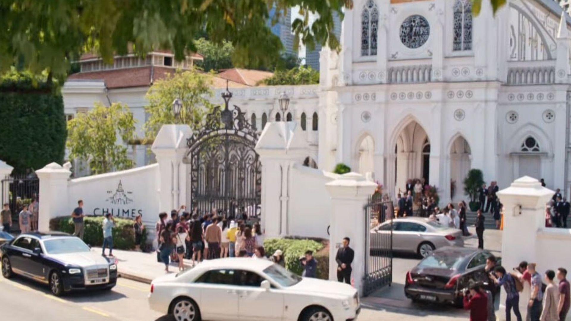 Luxury cars and crowds outside the ornate white gates of CHIJMES in Singapore.