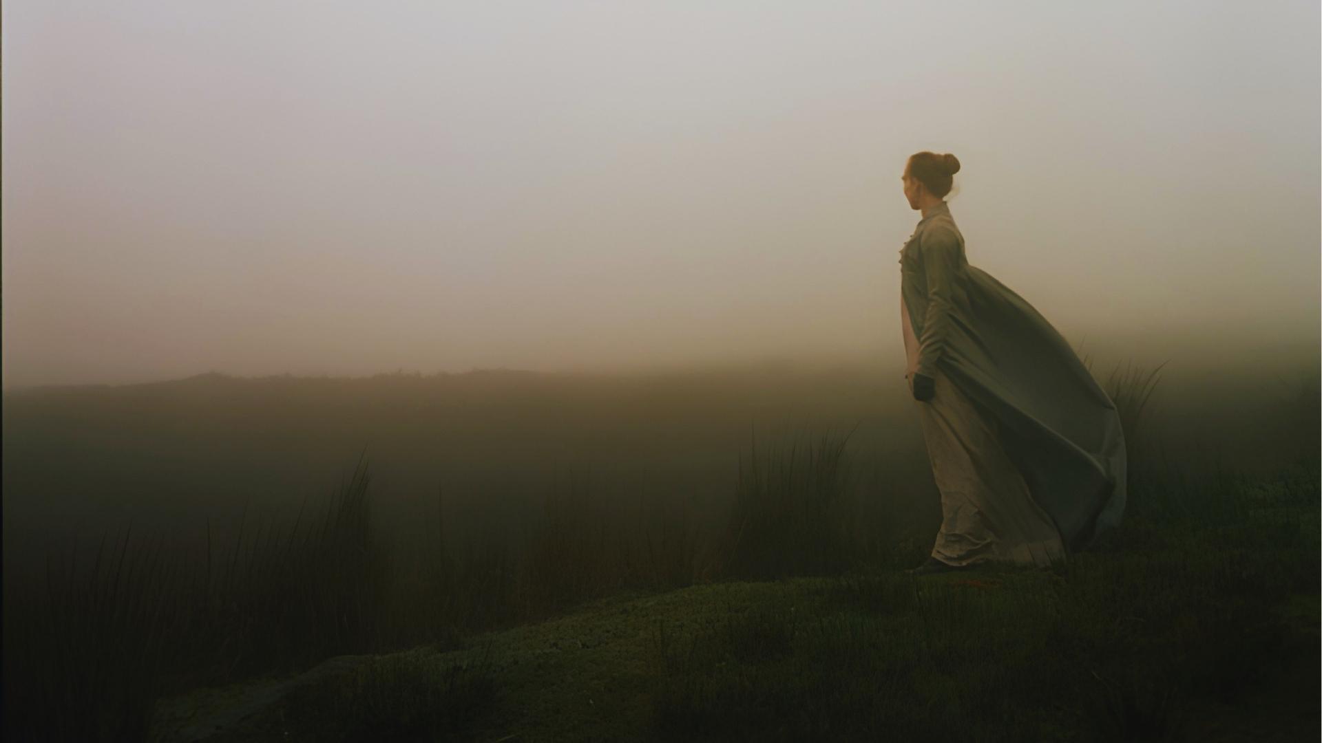 Woman in Victorian dress standing on foggy Yorkshire moors, Wuthering Heights filming location.