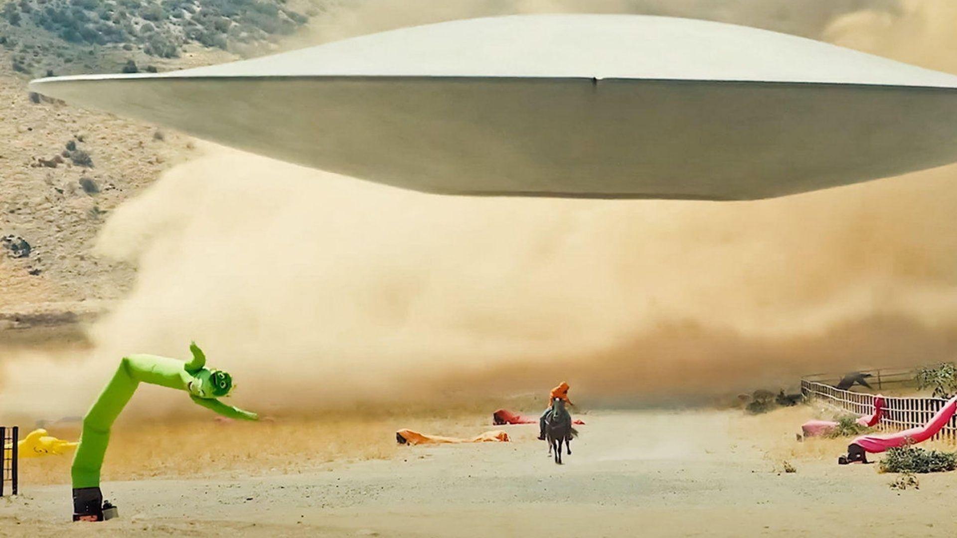 Still from NOPE. A massive alien saucer hovers low over Haywood Ranch in a thick dust storm, OJ rides toward it.