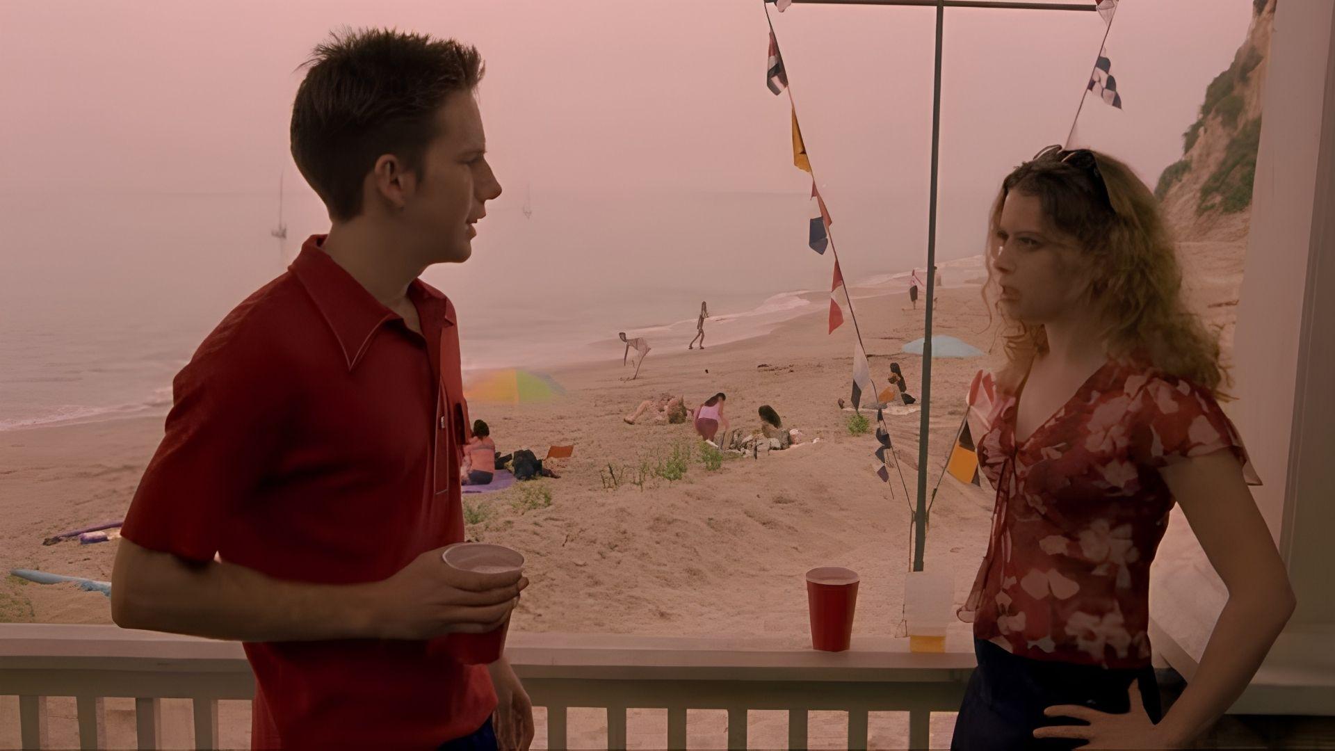 American Pie 2 still of actors talking on a beachfront porch with colourful flags and sunbathers below.