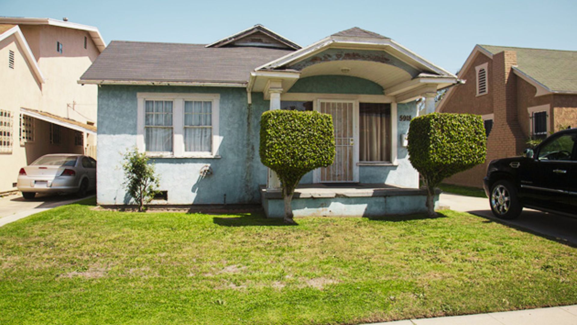 Light blue stucco house, number 5918, with manicured shrubs.