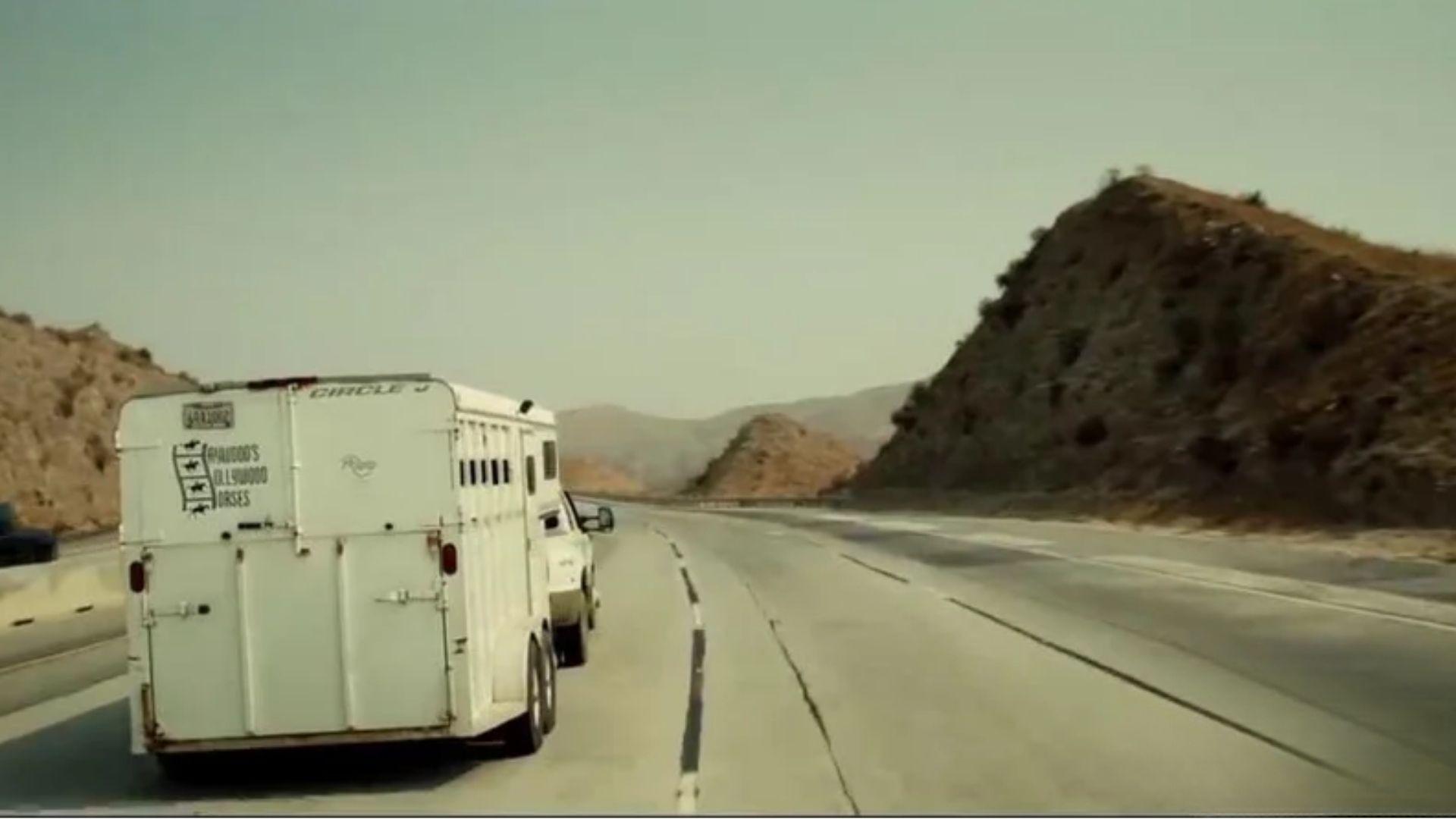 Still from NOPE. White Circle J horse trailer marked Haywood's Hollywood Horses on dry California freeway.