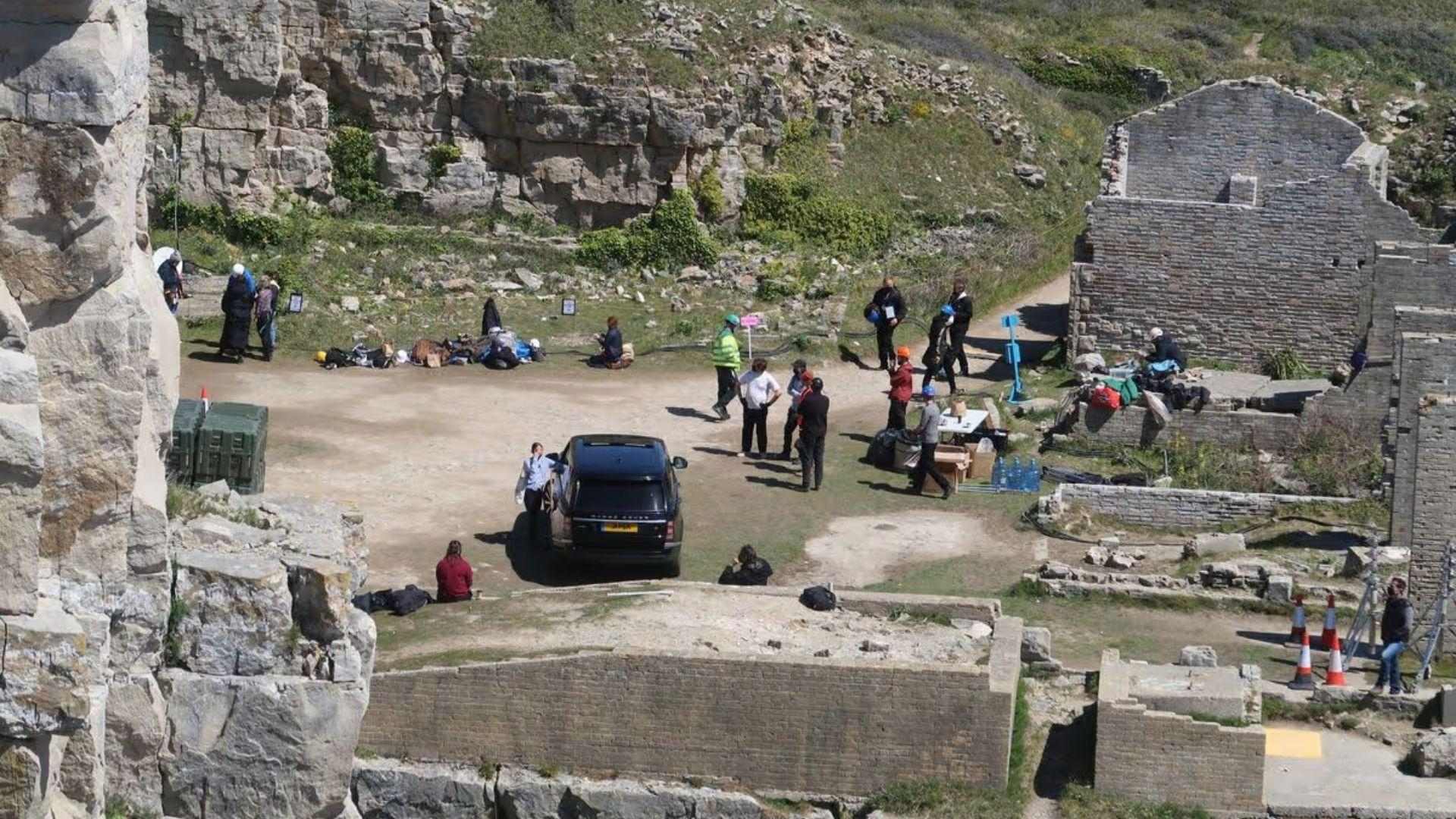 Behind-the-scenes at Winspit ruins, crew and cast gathered around a black Range Rover.