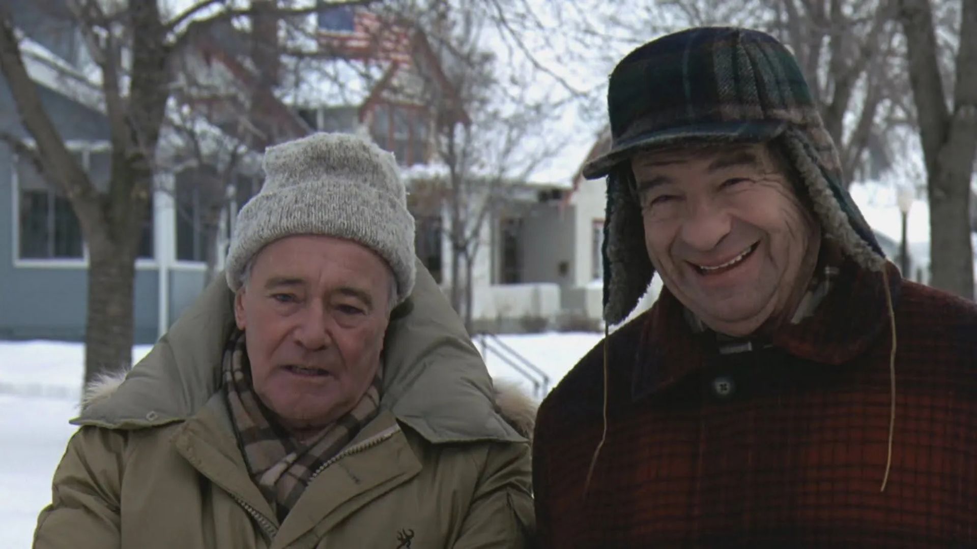 Two elderly neighbors in winter clothing standing outdoors in a snowy Minnesota scene from Grumpy Old Men.