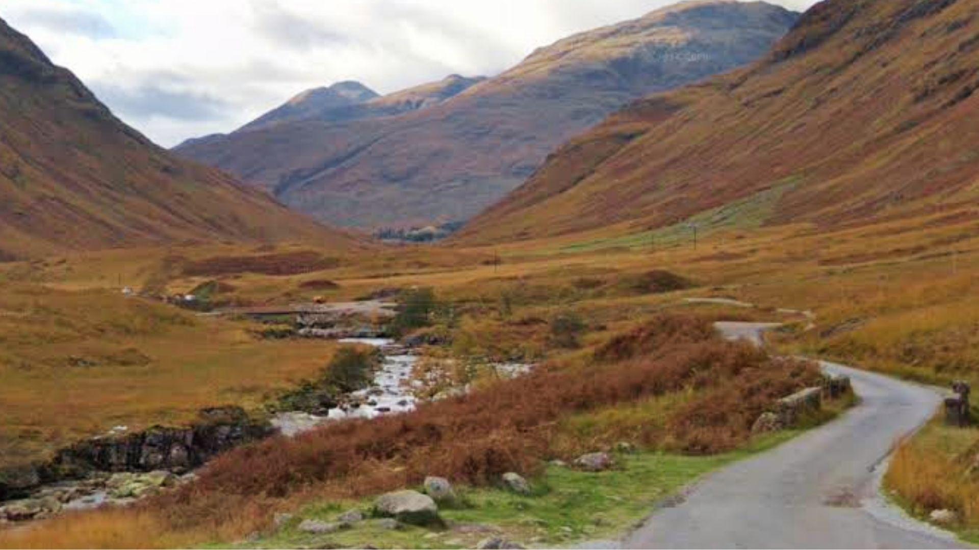 Sunlit green mountains of Glencoe Valley, Scotland, Skyfall road scene location