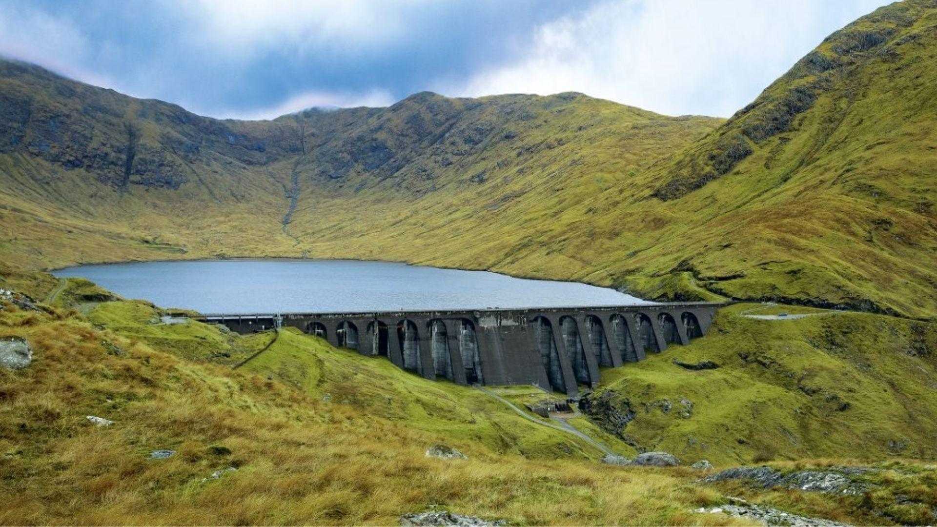 Cruachan Dam on Loch Awe, Scottish Highlands, with concrete arch buttresses amid green hills.