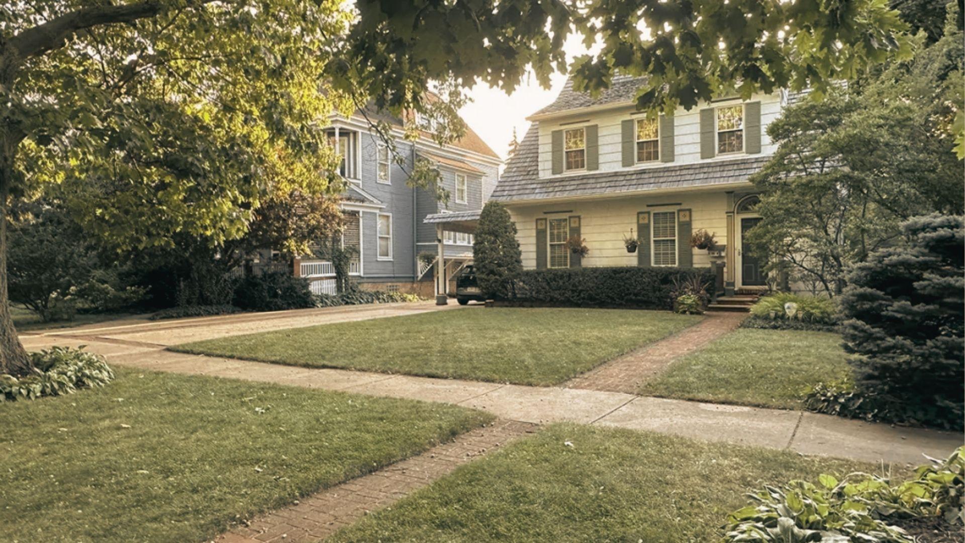 A well-maintained lawn features a walkway and several trees in the front yard, creating a serene outdoor space.