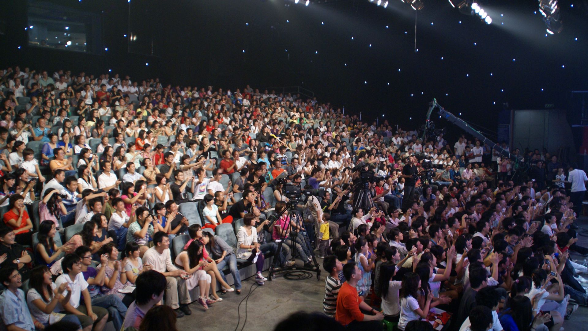 A large crowd gathers in an auditorium during the filming of a Friends TV series episode.